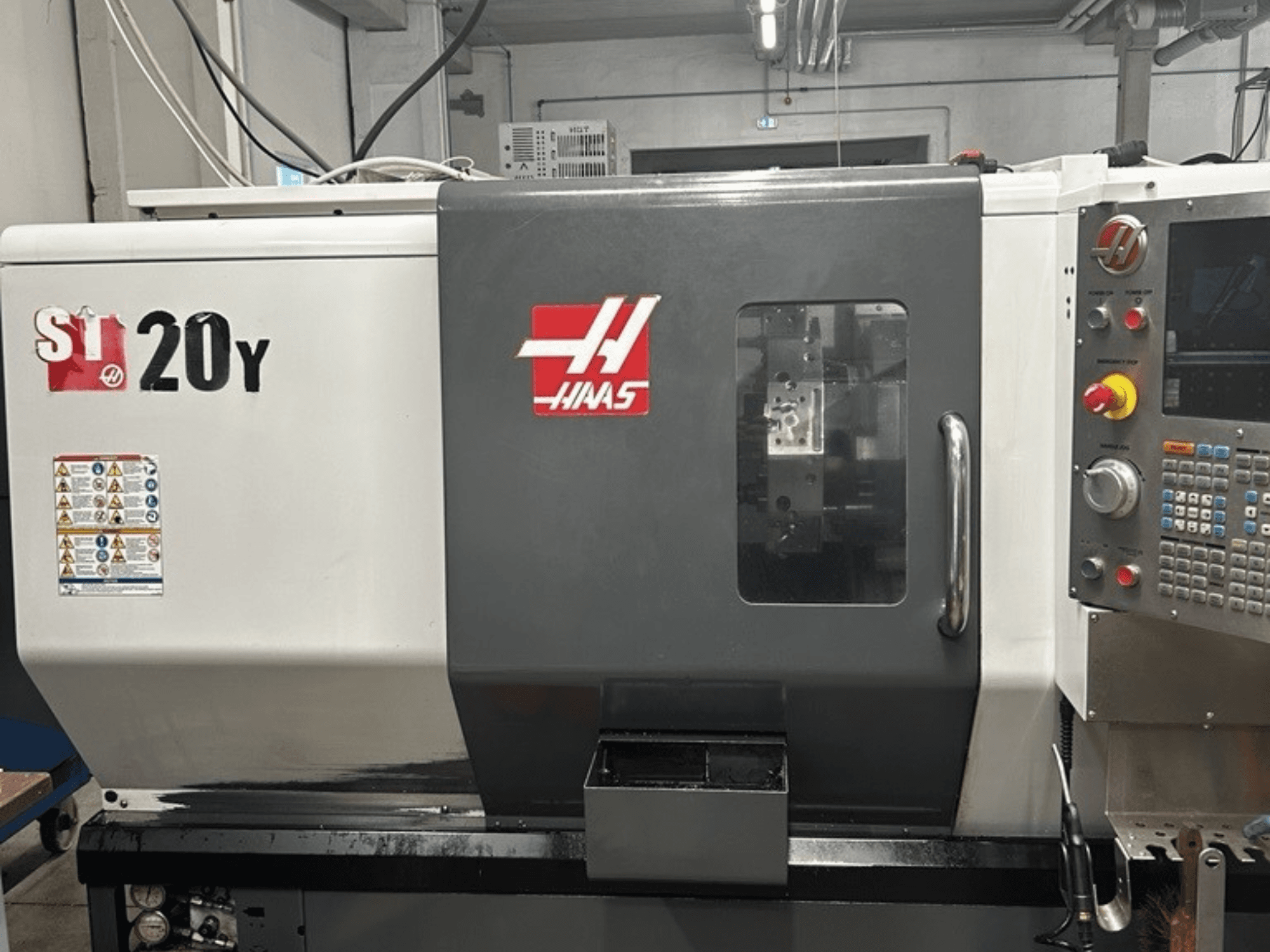 Haas ST-20Y CNC-svarv, framifrån, med kontrollpanel, säkerhetsetiketter och driftfönster.