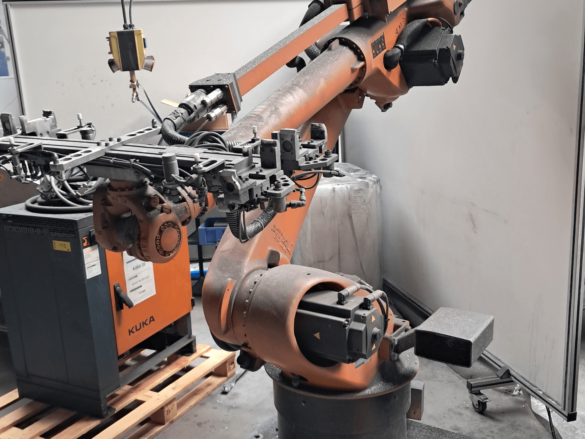 Robotarmen KUKA KR 30L16-2 i sidovy, med en komplex ändeffektor och styrkablar, placerad bredvid en KUKA-styrbox.
