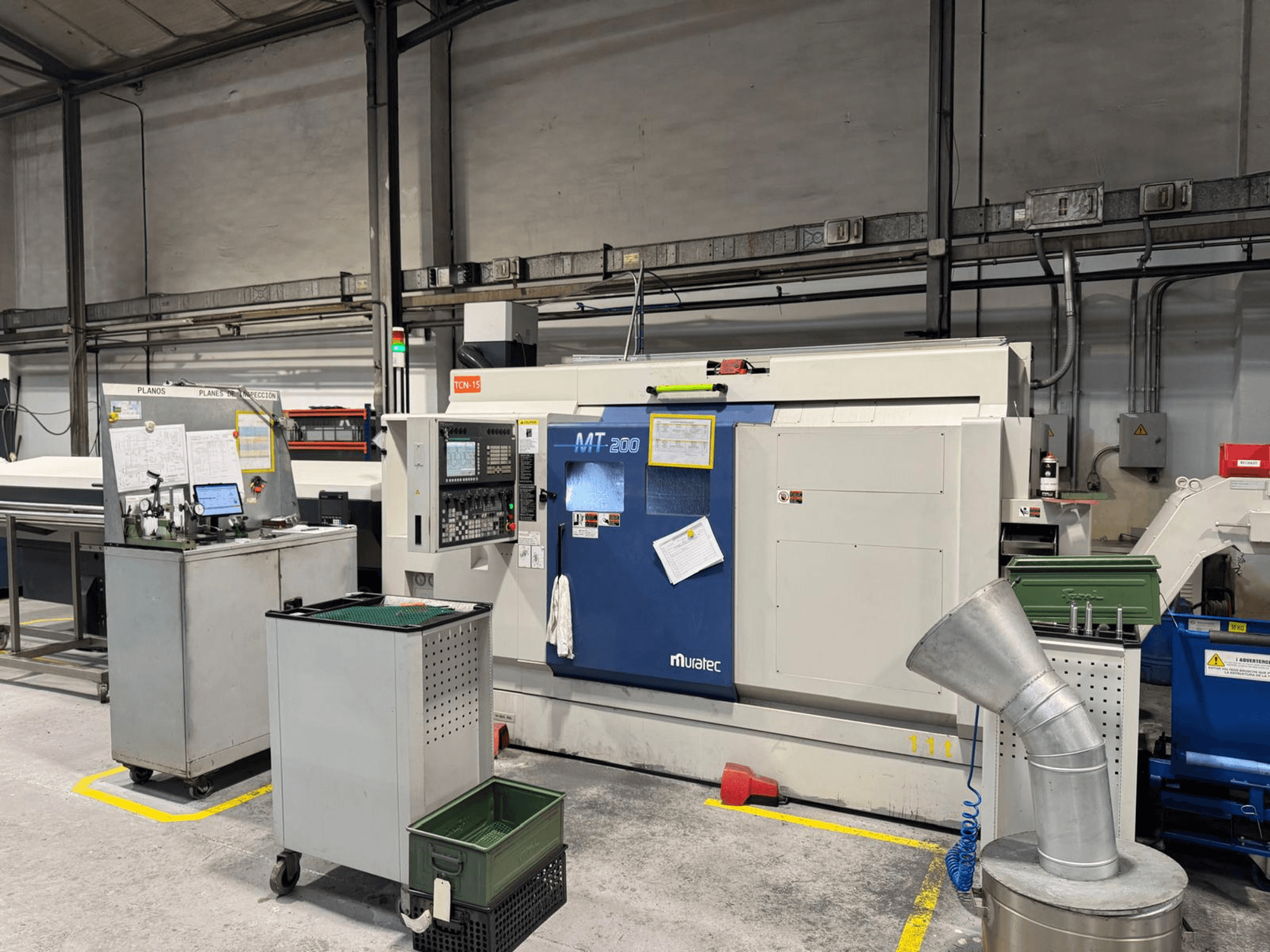 Muratec MT200 flerspindlig svarv i fabriksmiljö, sedd framifrån, med kontrollpanel och kringutrustning.