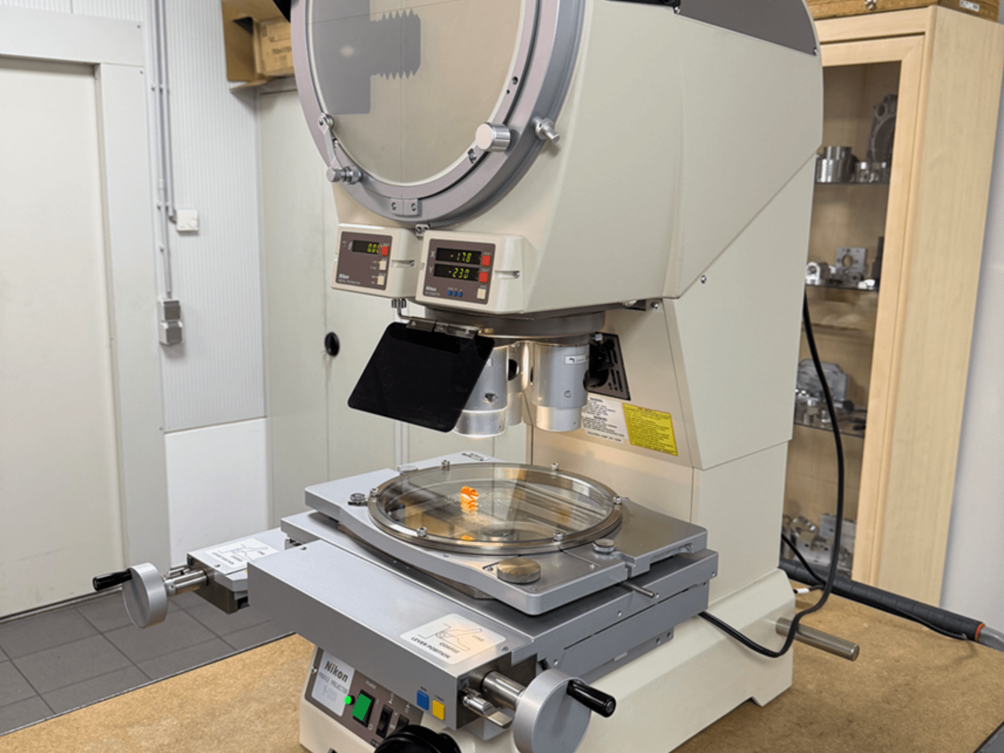 Nikon modellmikroskop sett framifrån, med digitala displayer, ett justerbart bord och en cirkulär glasplatta.