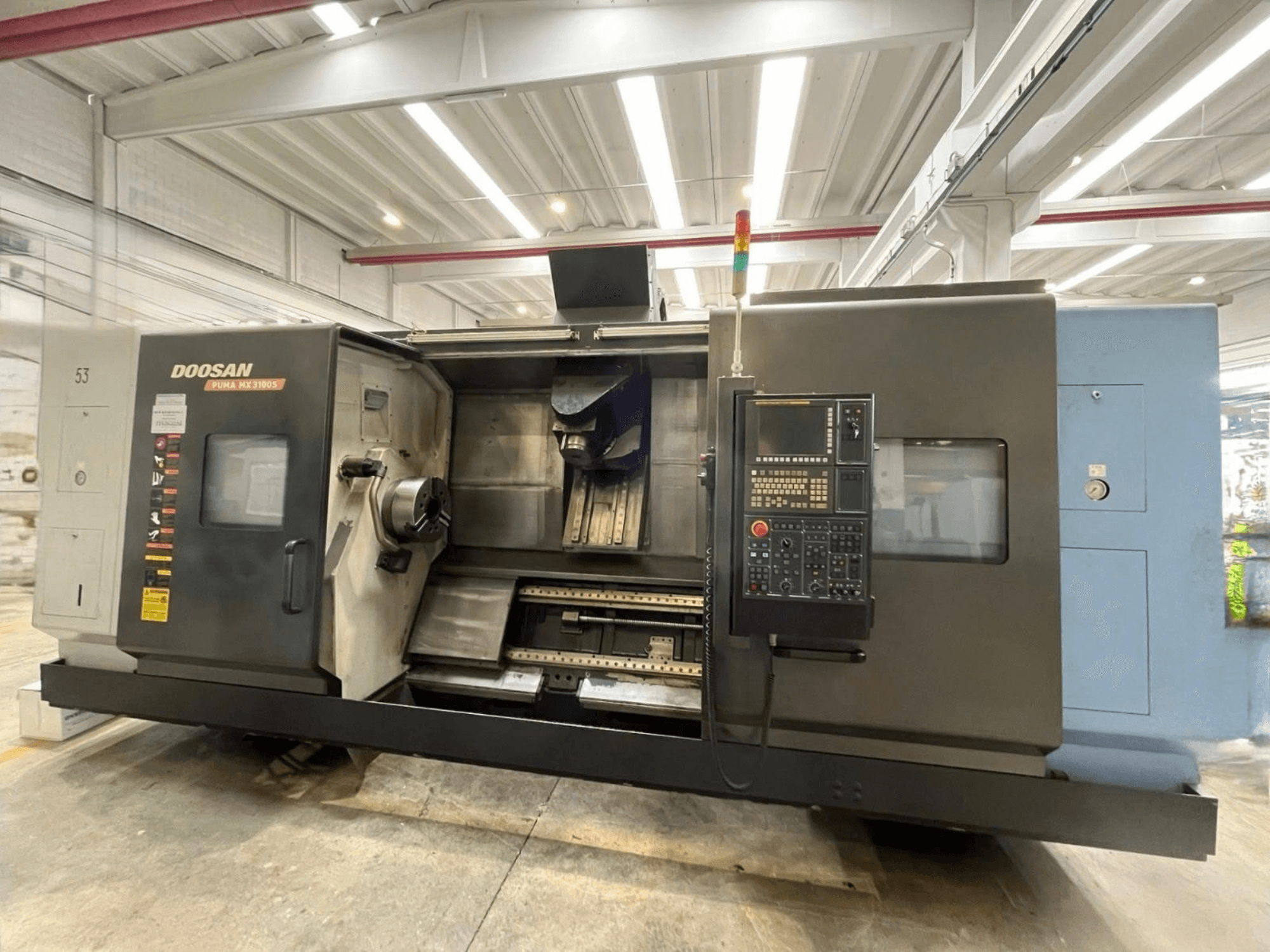Framifrån sett på en DOOSAN PUMA MX3100 horisontell svarv med kontrollpanel samt synlig spindel och verktygshållare.