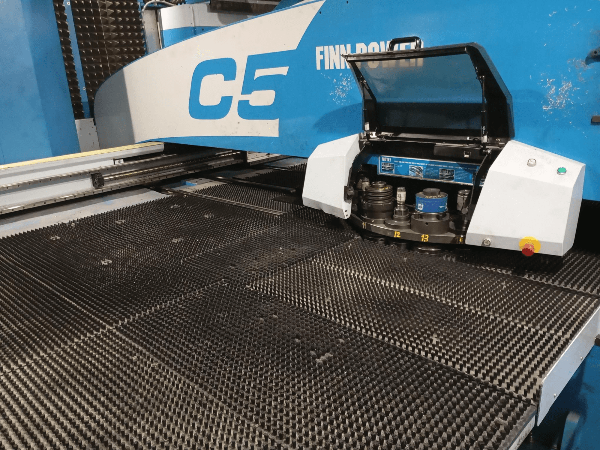 Finn-Power C5 stansmaskin, vy framifrån, med verktygshuvudet öppet över ett strukturerat arbetsbord med numrerade indexeringspunkter.