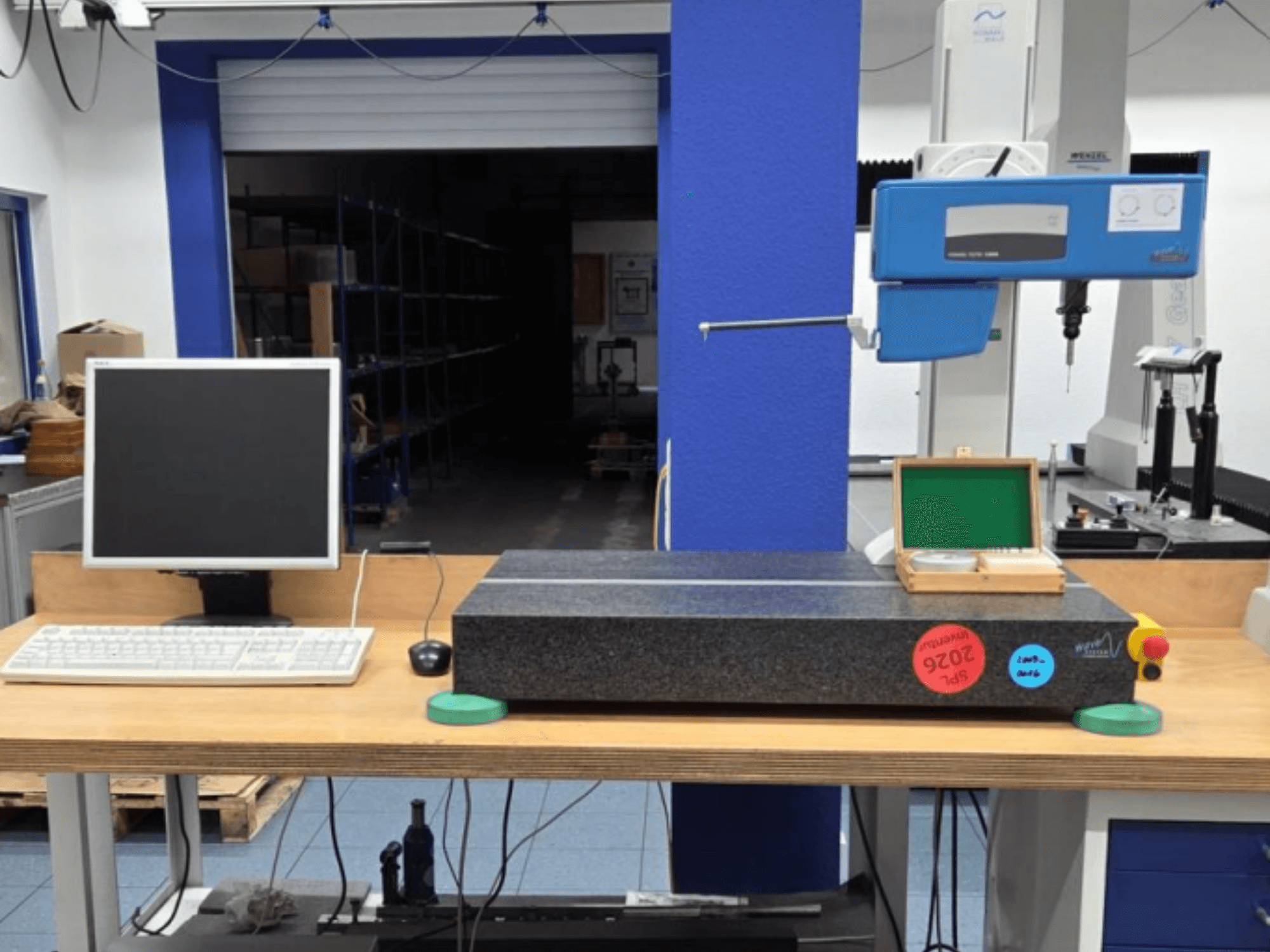 JENOPTIK wave C8000 CMM i en verkstad, med monitor, tangentbord och mätyta av granit. Vy framifrån.