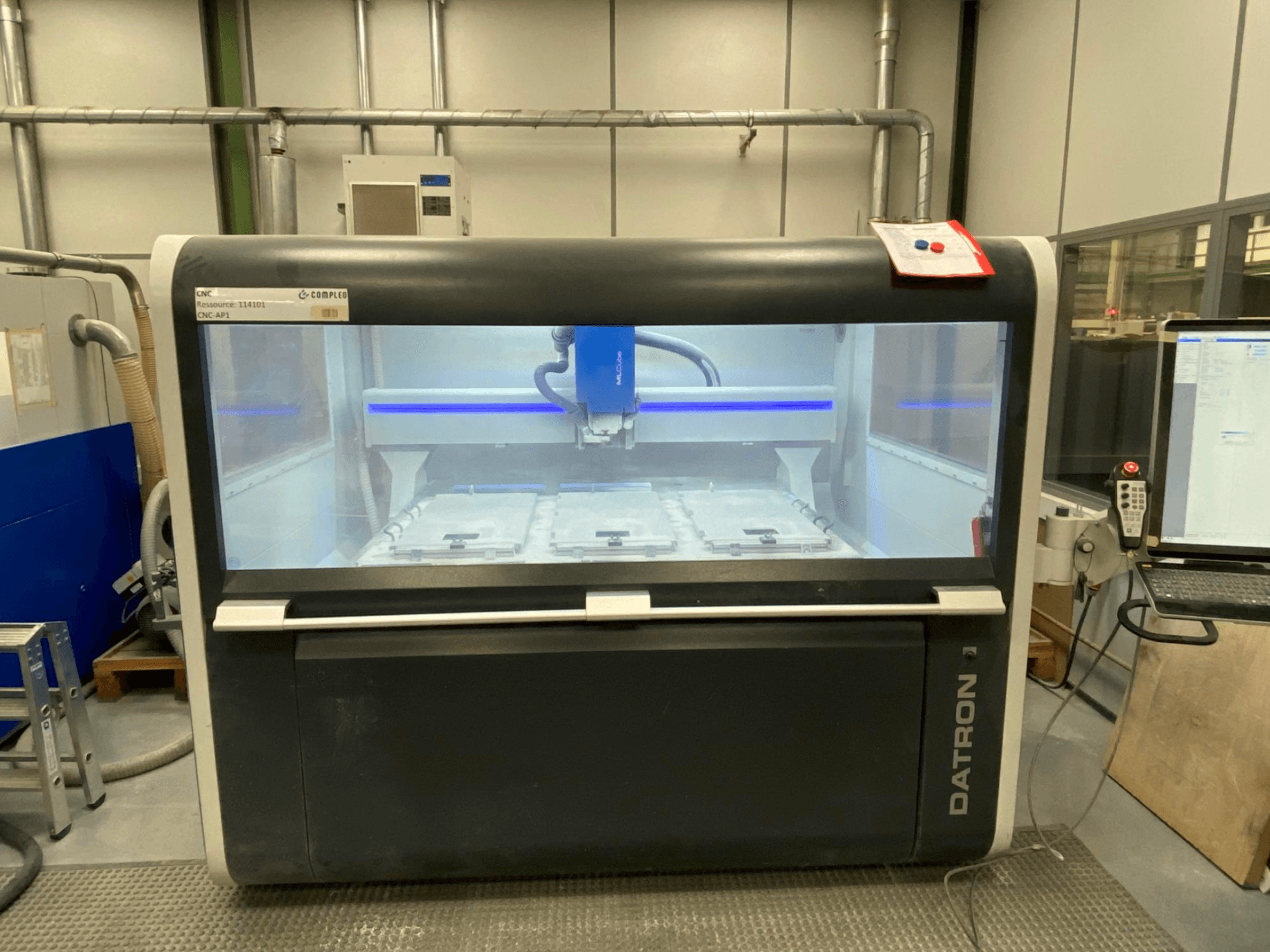 Datron MLCube B vertikal bearbetningscenter, framifrån, visar maskinens interiör och kontrollpanel.