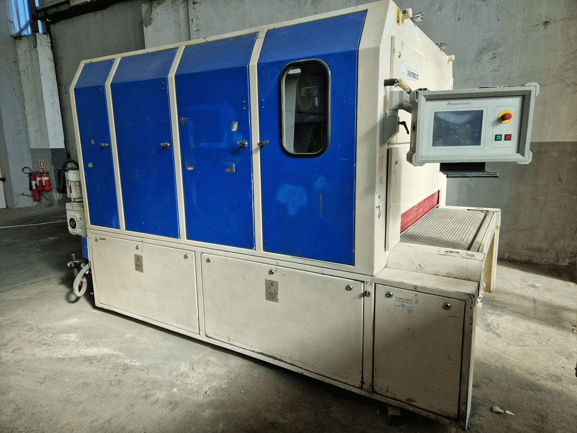 Industrimaskin av märket "Sedecom", vy från sidan; har blå paneler, en kontrollskärm och en strukturerad yta för hantering av produkter.