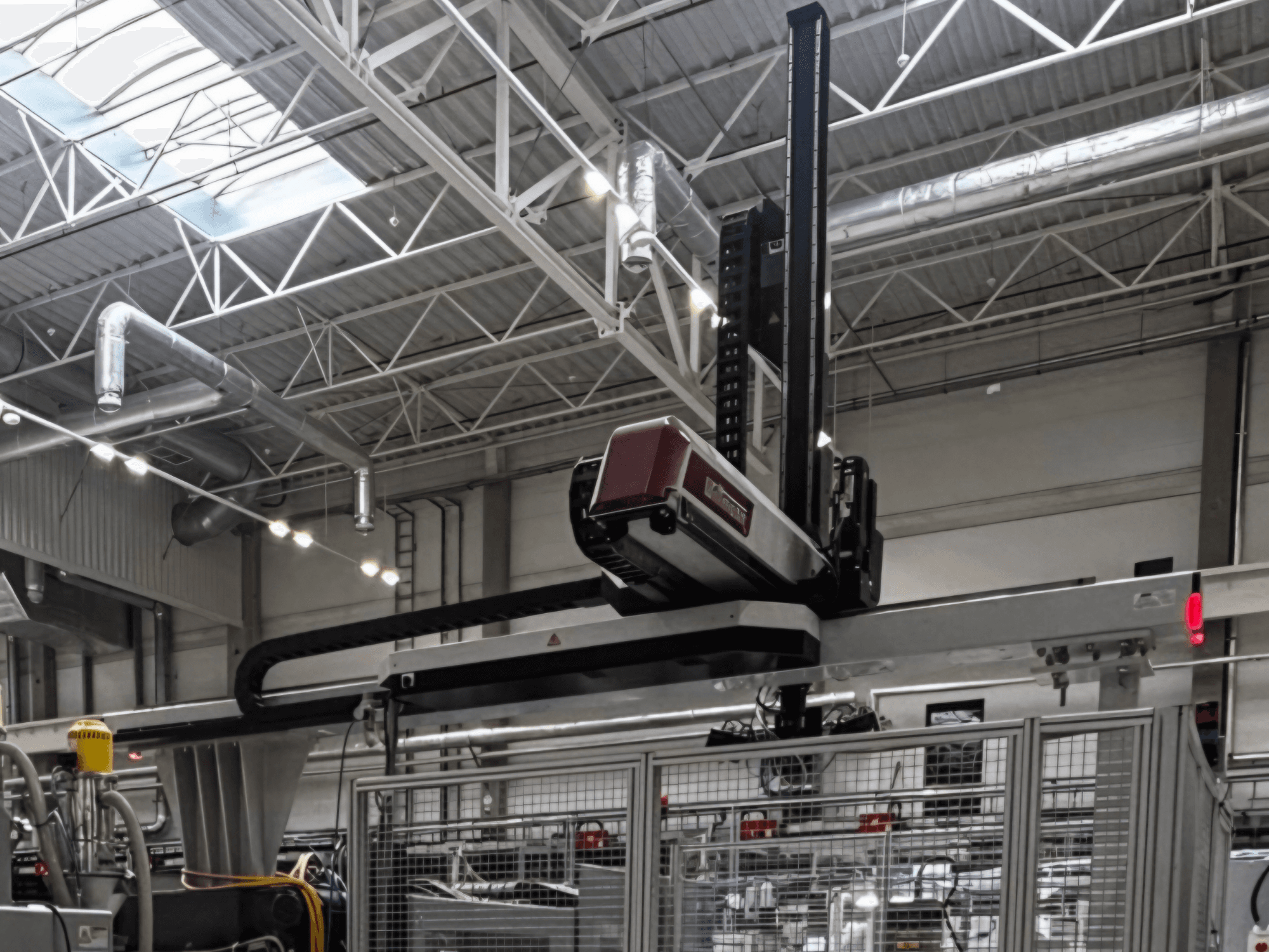 Plastbearbetningsmaskin av typen WITTMANN W832PRO i fabriksmiljö, sidovy som visar det överliggande systemet och den industriella bakgrunden.