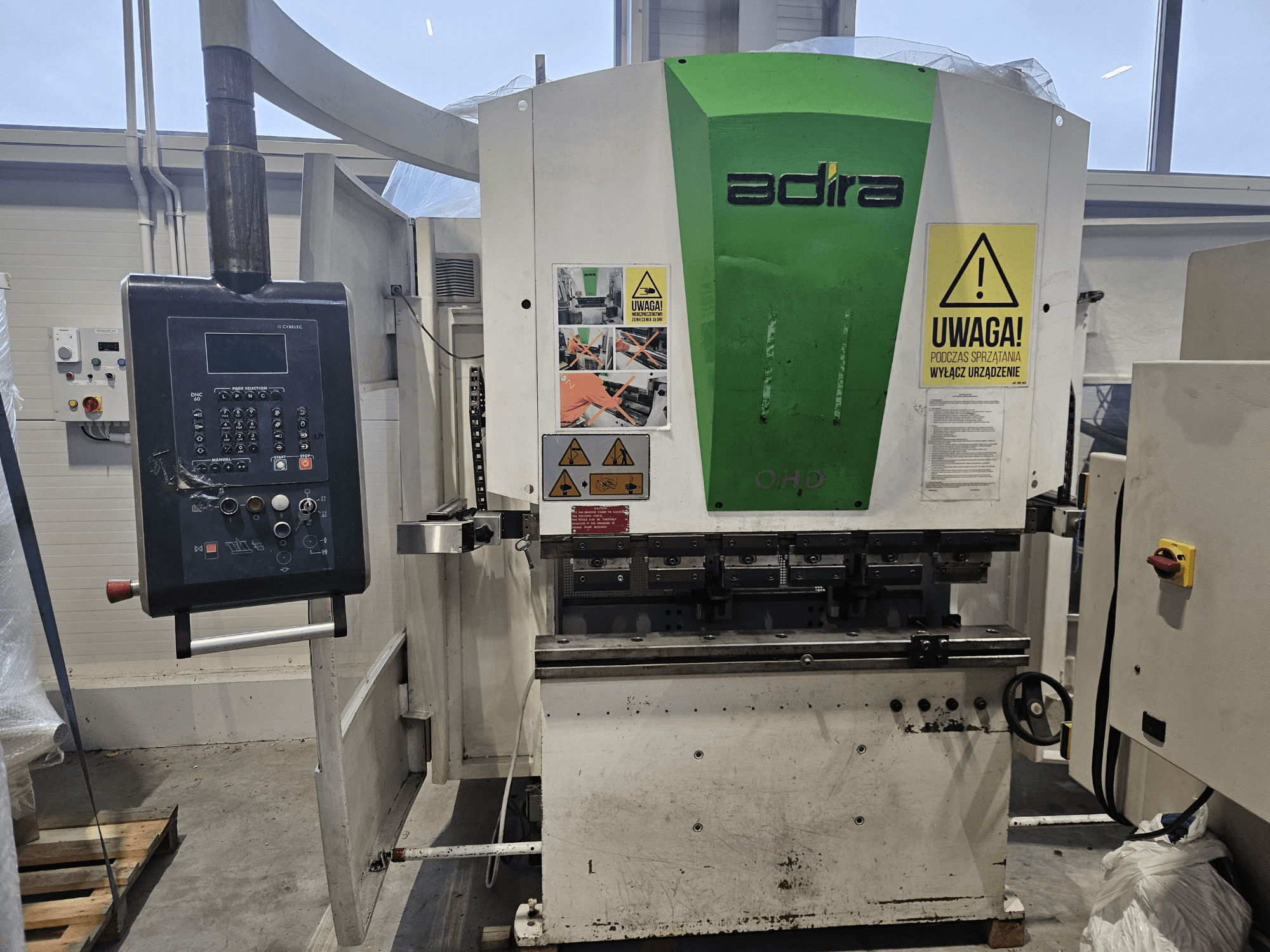 Adira OHD-maskin sedd framifrån, med kontrollpanel, säkerhetsvarningar och manöverknappar.