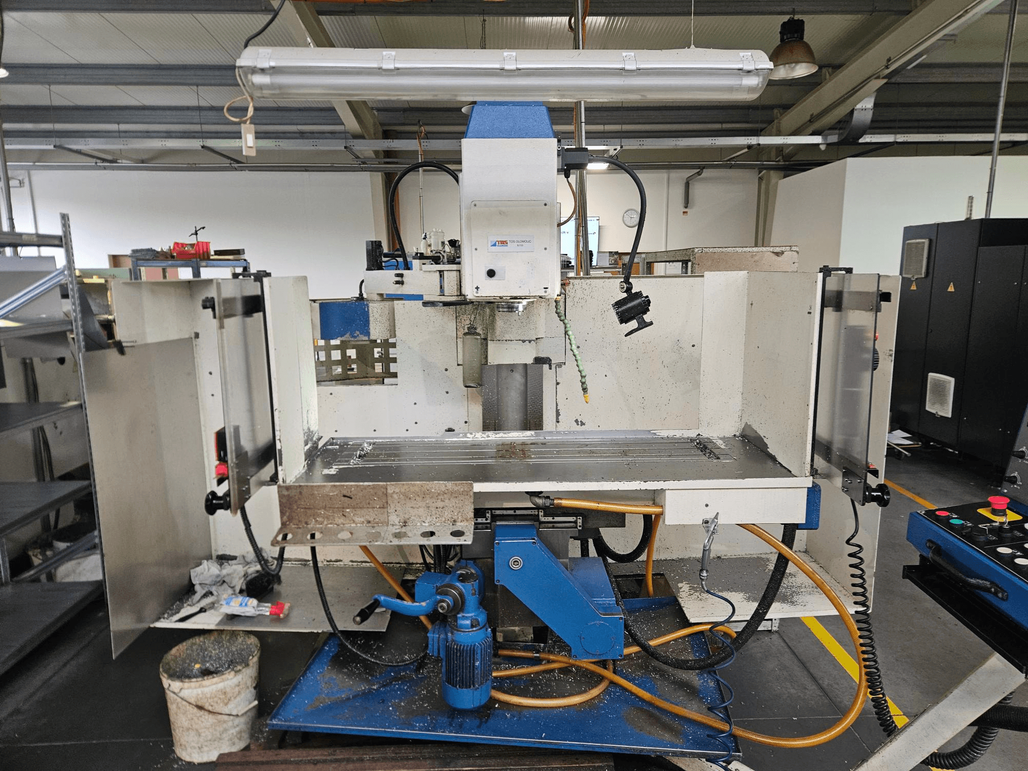 TOS Olomouc FV30 CNC En vertikal bearbetningscenter i en verkstad, framifrån med kontrollpanel, arbetsbord och kylsystem.