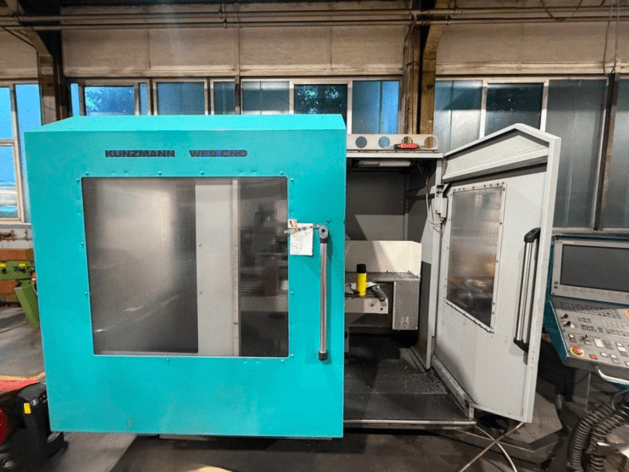 KUNZMANN WF9 CNC vertikalt bearbetningscenter, framifrån med öppna dörrar som visar interiören och kontrollpanelen.