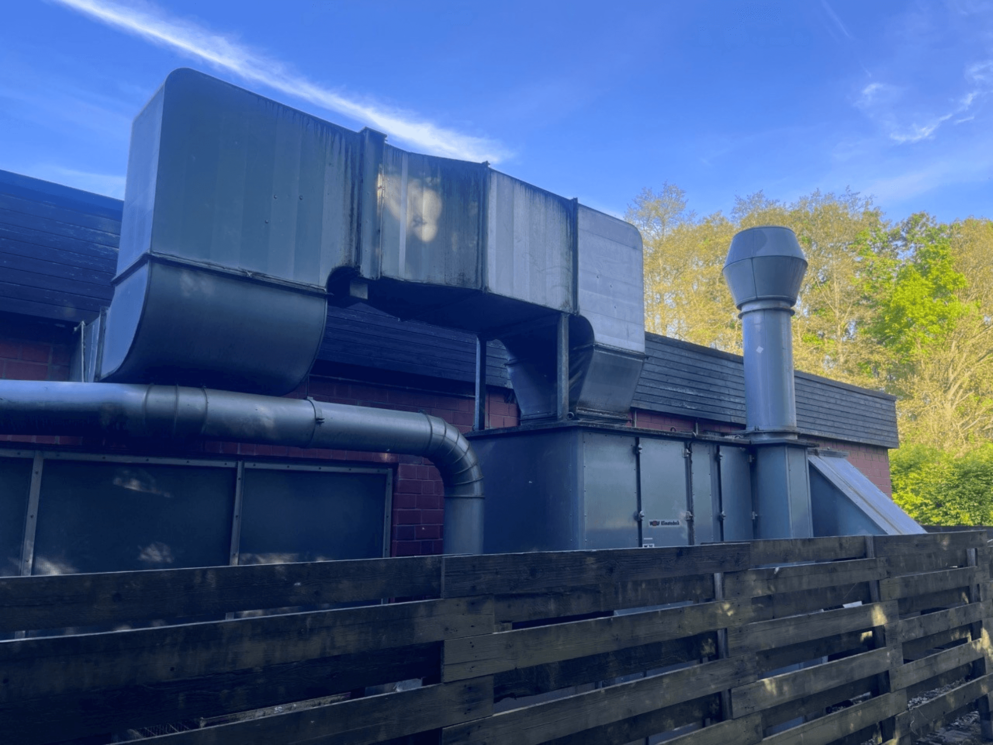 Industriellt ventilationssystem med metallkanaler, sett från sidan; inkluderar en kvadratisk och cylindrisk skorsten, grön finish.