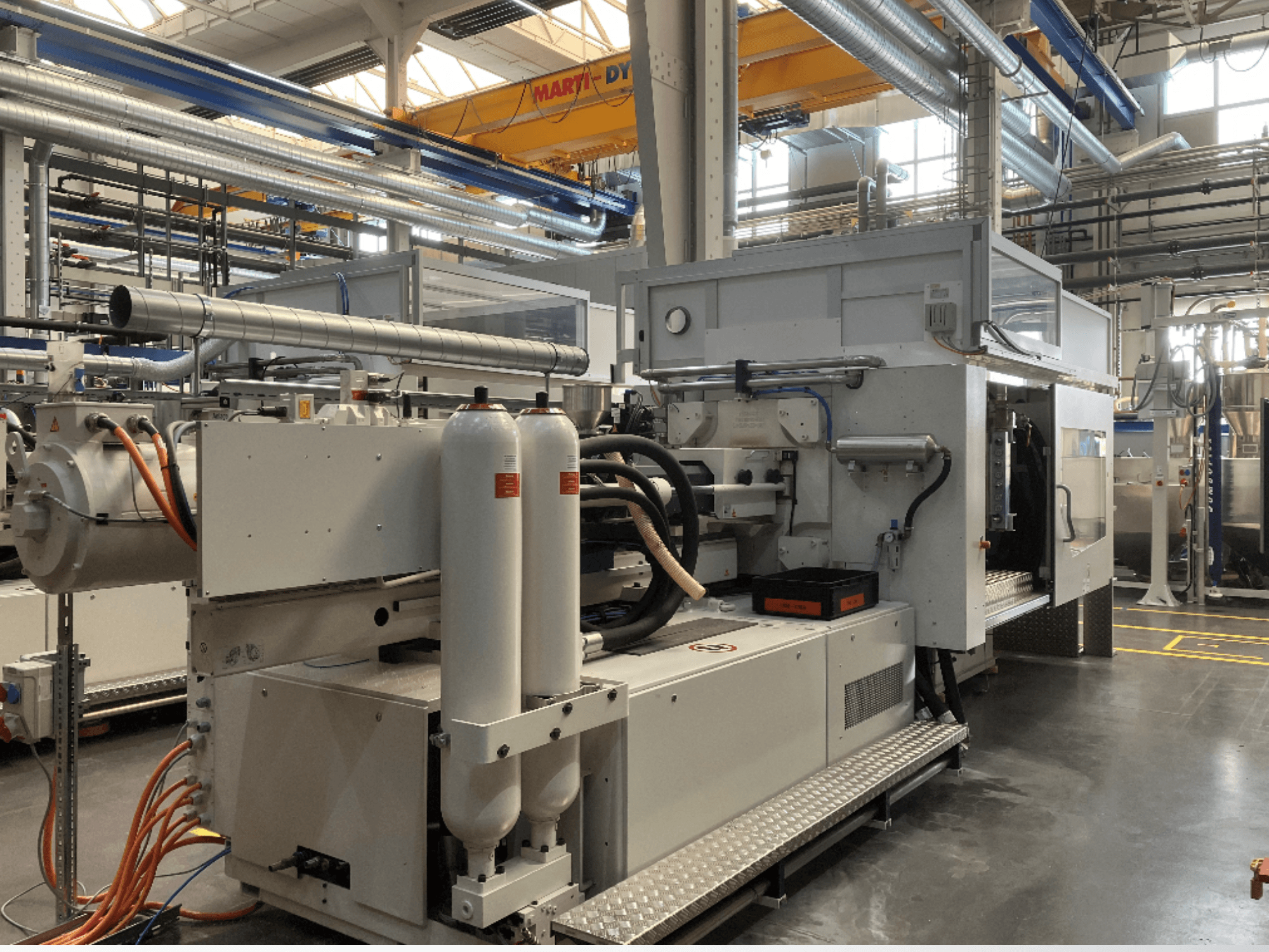 Industrimaskin i sidovy med flera slangar, två vertikala tankar och kontrollpanel; märke/modell ej synlig.