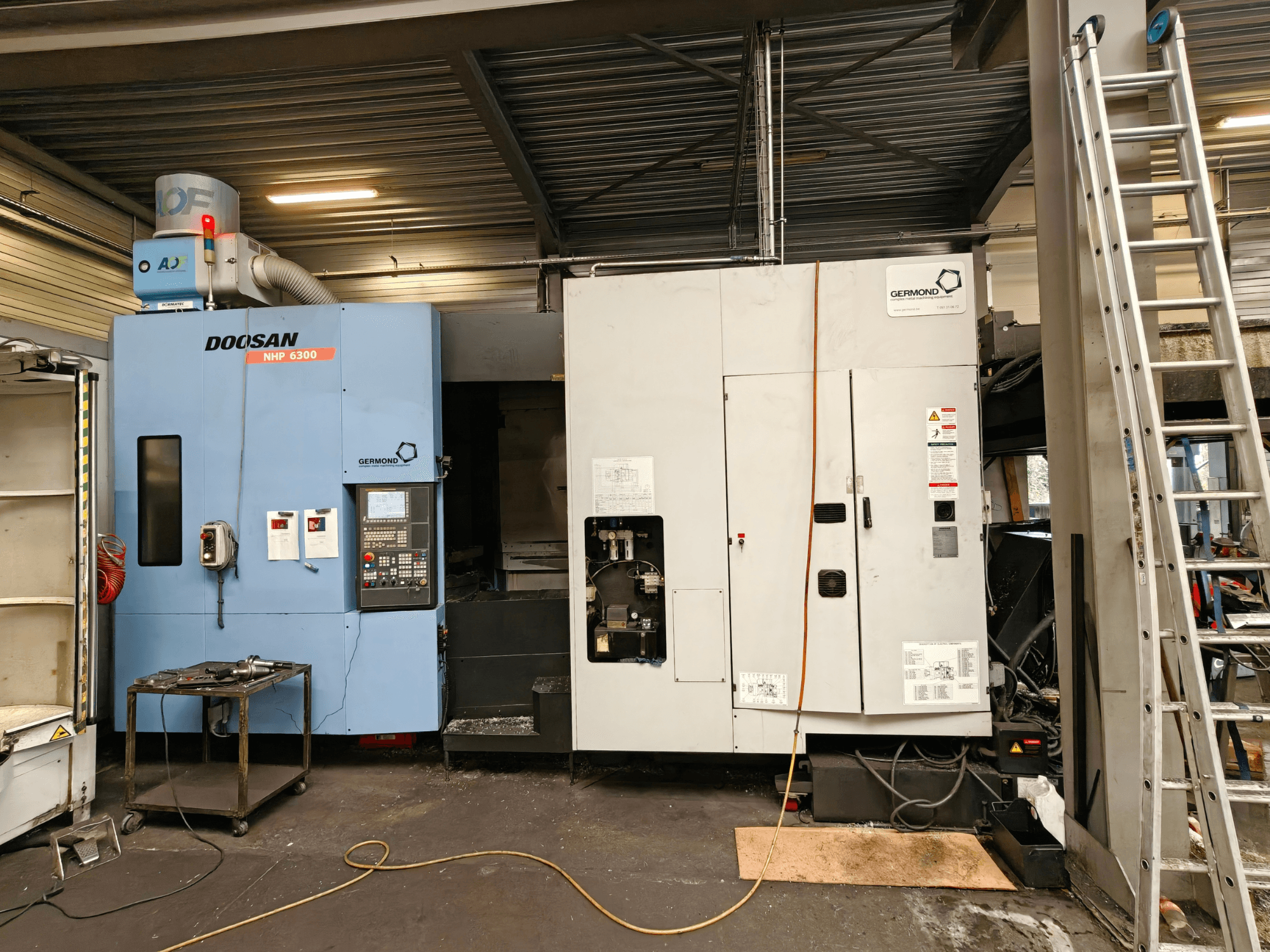DOOSAN NHP6300 horisontellt bearbetningscenter sett framifrån, där kontrollpanelen och intilliggande maskiner visas i en verkstadsmiljö.
