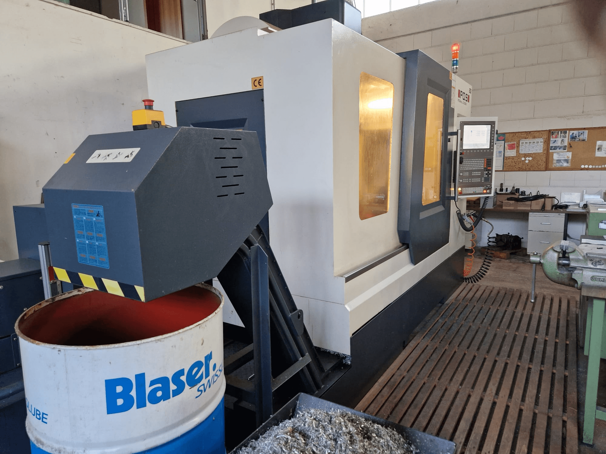 Frontvy av POSmill C 1050 vertikal fleroperationsmaskin, med kylsystem ovanför Blaser-trumman och kontrollpanelen synlig.