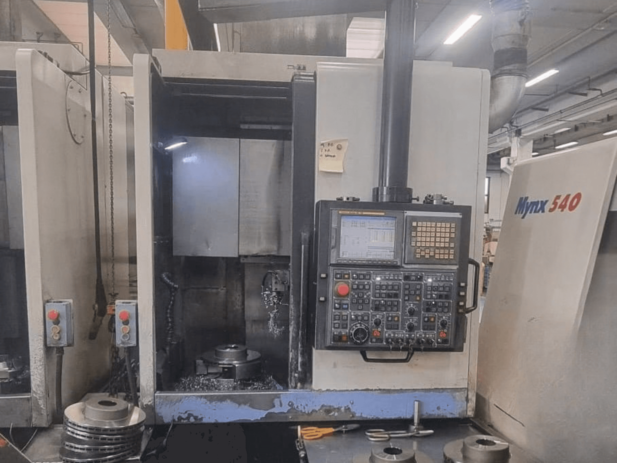 Framifrånvy av en vertikal svarv av typen DOOSAN PUMA V400-2SP, där man ser kontrollpanelen och hur arbetsstycket är placerat inuti maskinen.