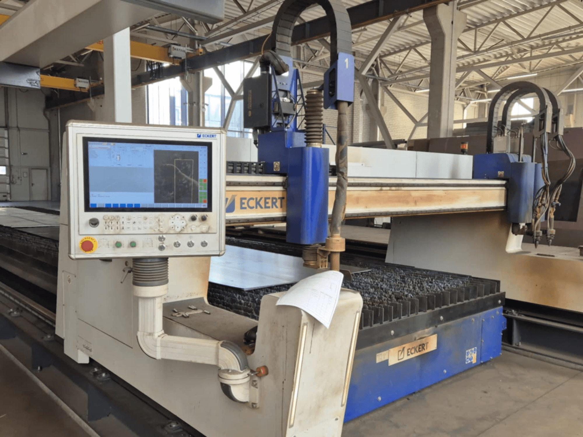 ECKERT CNC-skärmaskinens kontrollpanel framifrån, med pekskärm och olika manöverknappar.