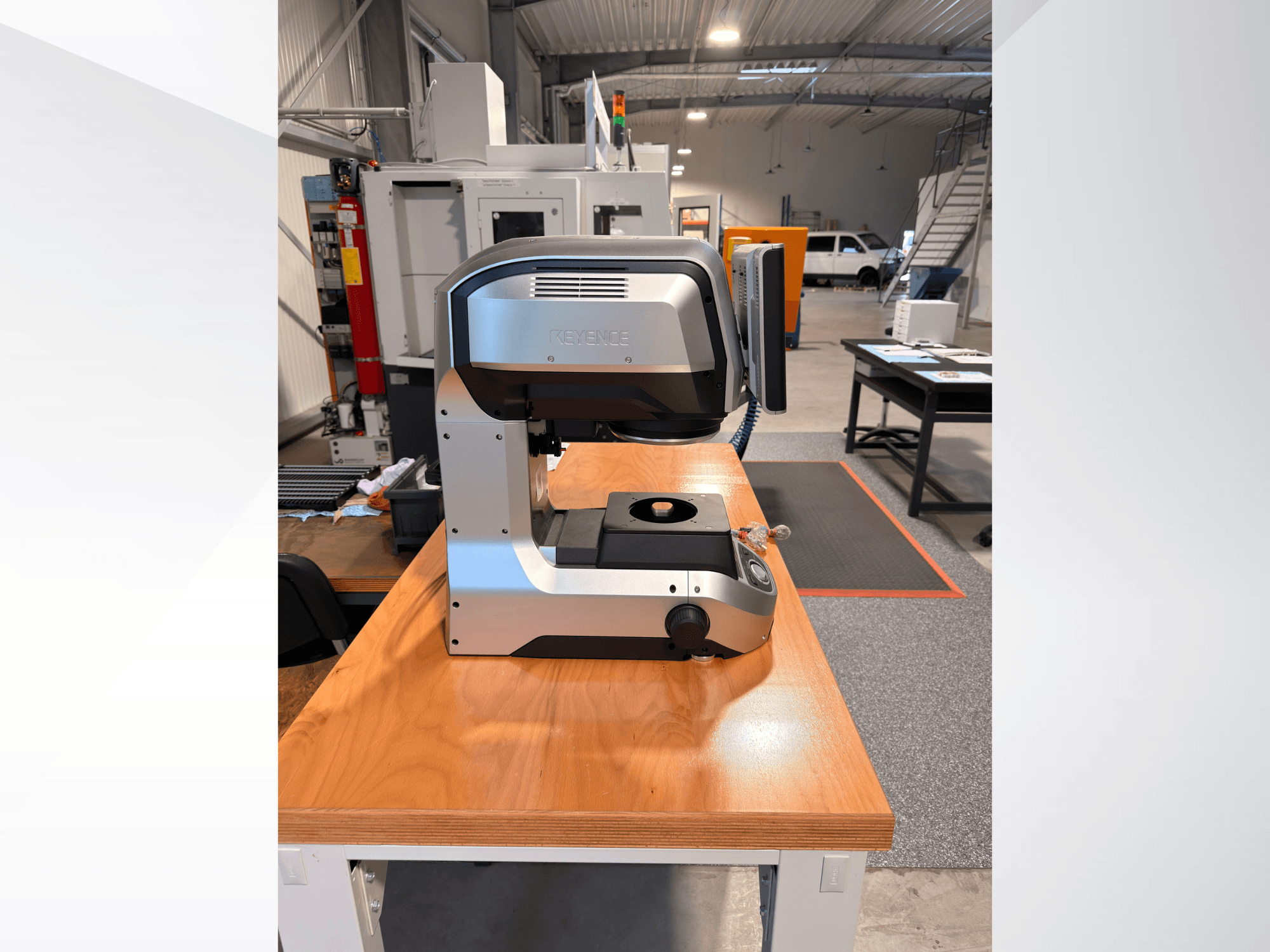 Framifrånbild av KEYENCE IM-8005 optisk mätmaskin på ett träbord, där dess eleganta design och användargränssnitt framhävs.