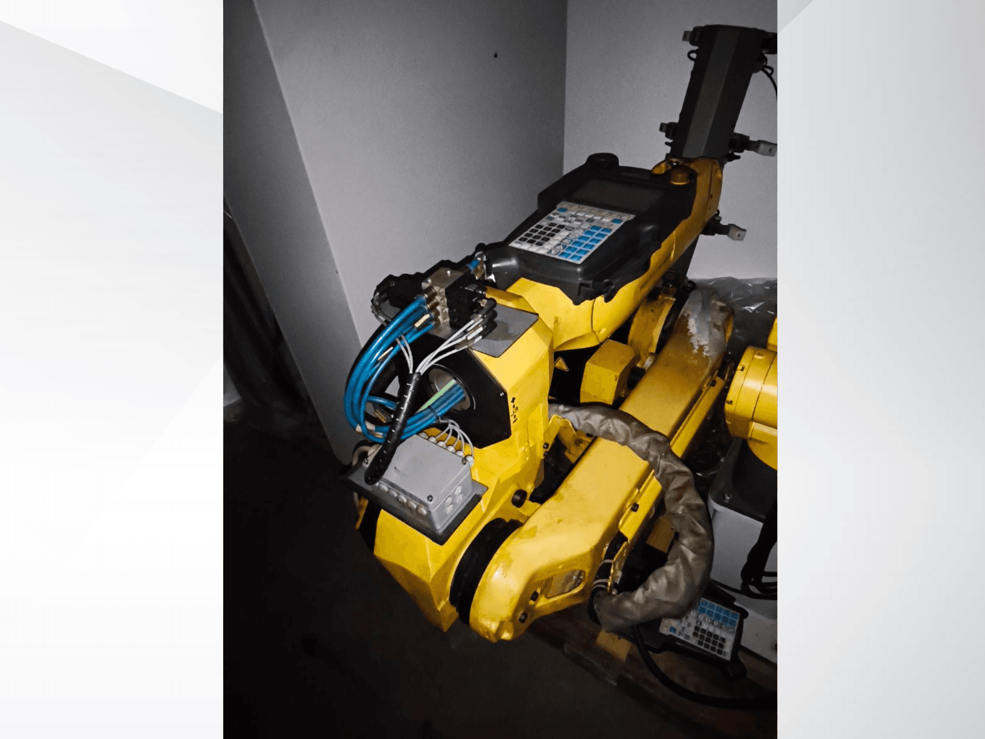 FANUC M-20iA robotarm i sidovy, med gul kropp, kontrollpanel och anslutna kablar.