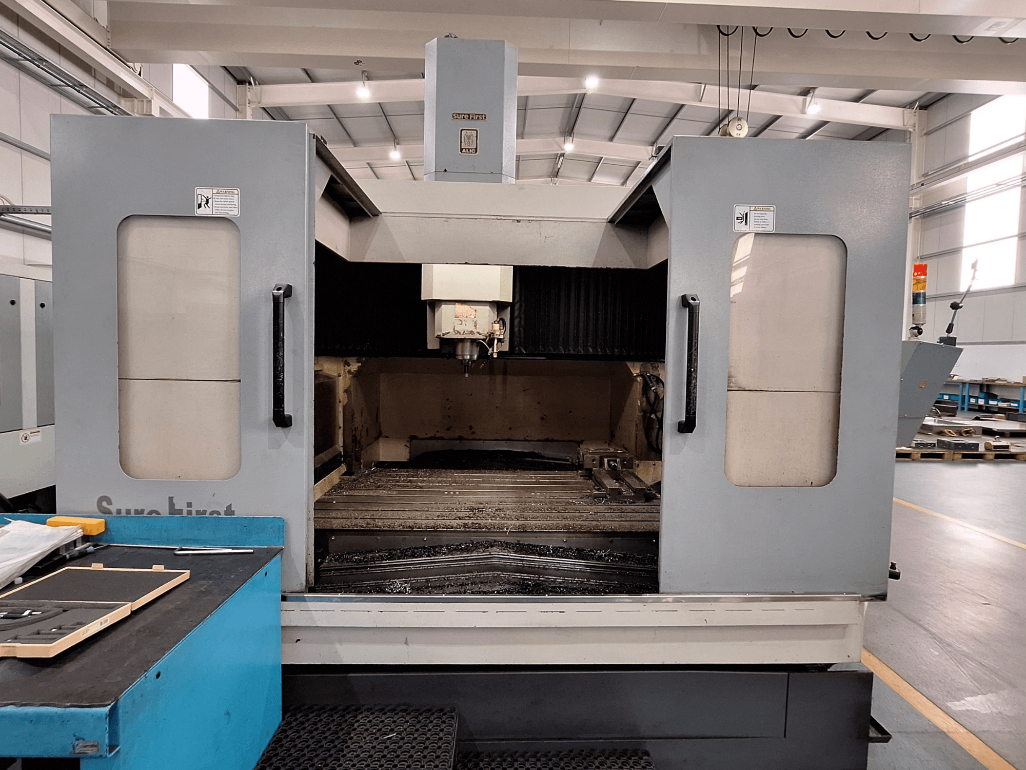 Vertikalt bearbetningscenter Sure First QM-1836, framifrån med verktygshuvud och tomt arbetsområde, modern industrimiljö.