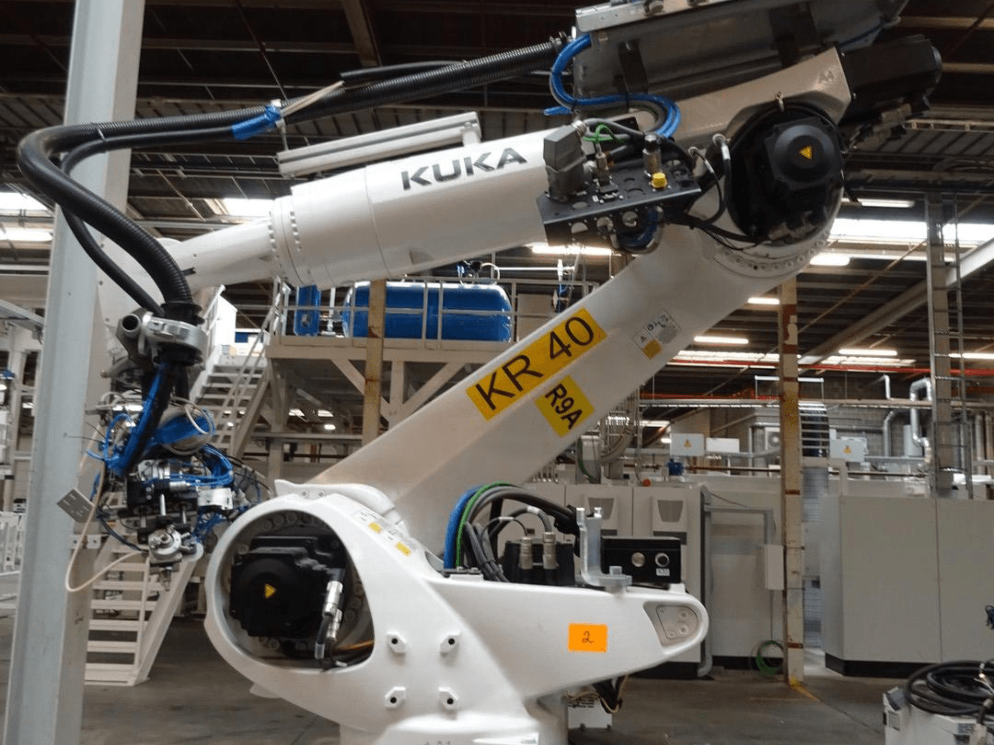 KUKA KR 120 R3100-2 robotarm i sidovy, med kontrollpanel och mekaniska komponenter, placerad i en industriell miljö.