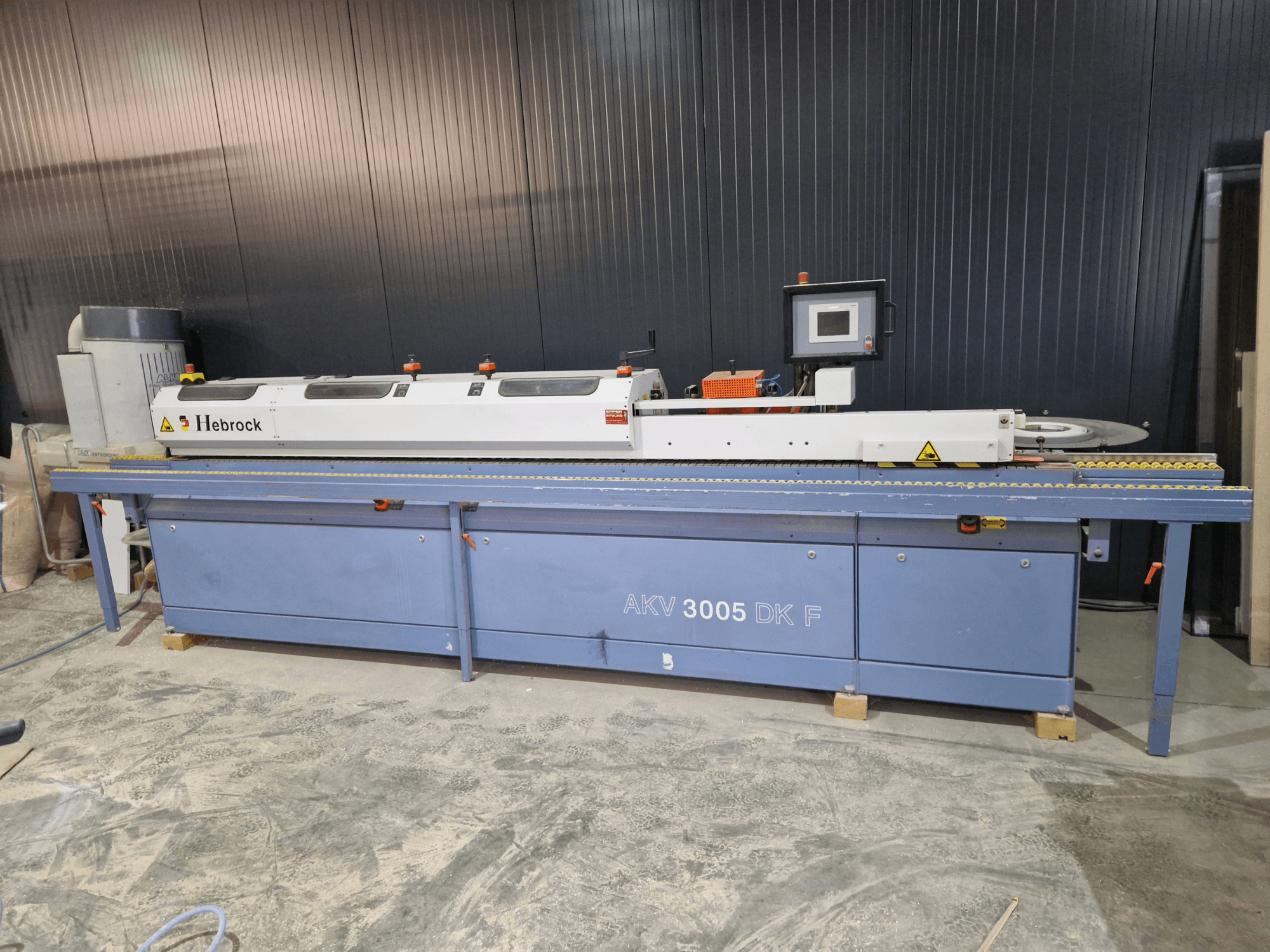 HEBROCK AKV 3005 DK-F kantlistmaskin, framifrån, med kontrollpanel, matarband och justerbara inställningar.