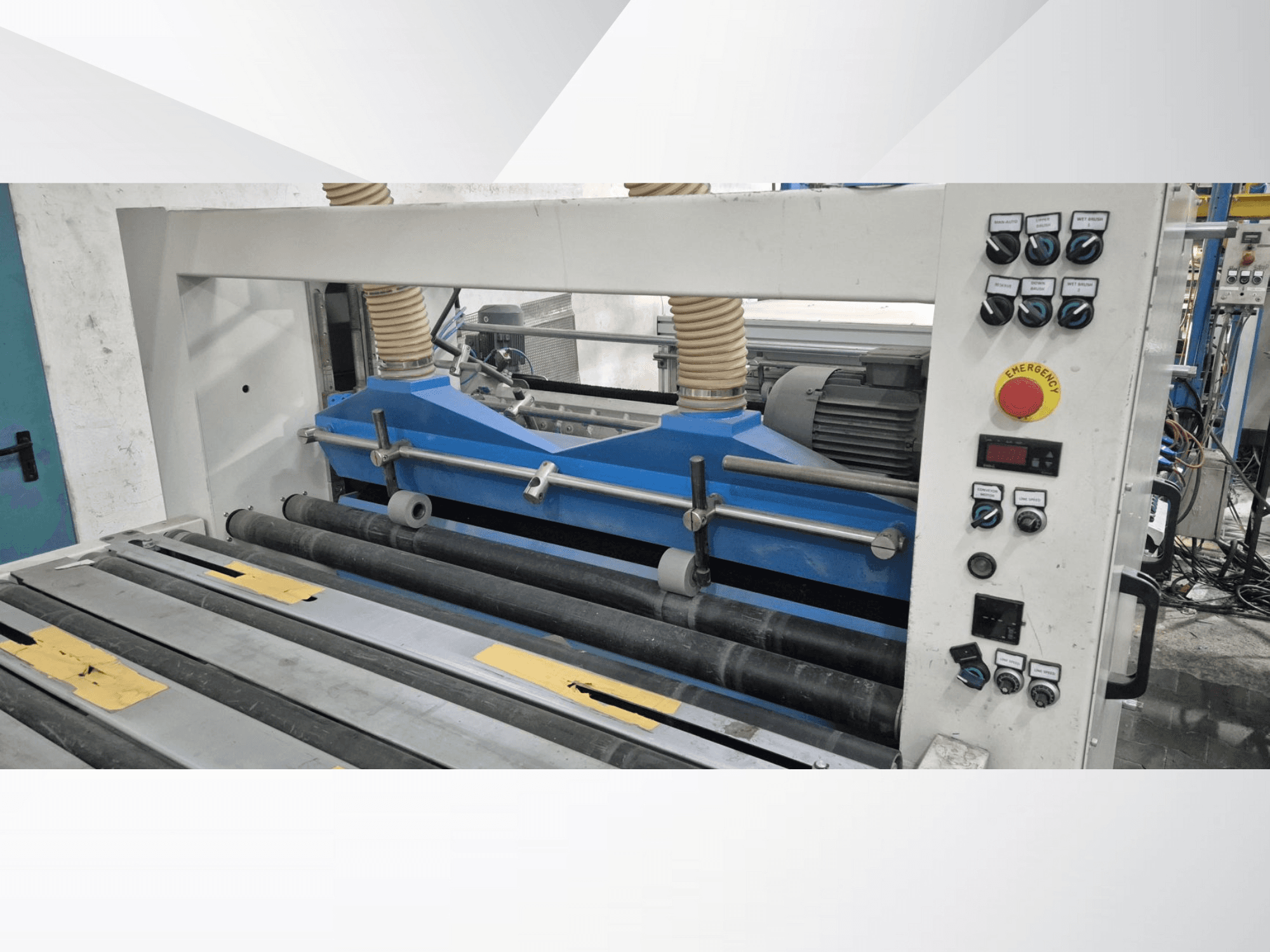 Industriell rullmaskin med blå komponenter, framifrån, med kontrollpanel och nödstoppsknapp.