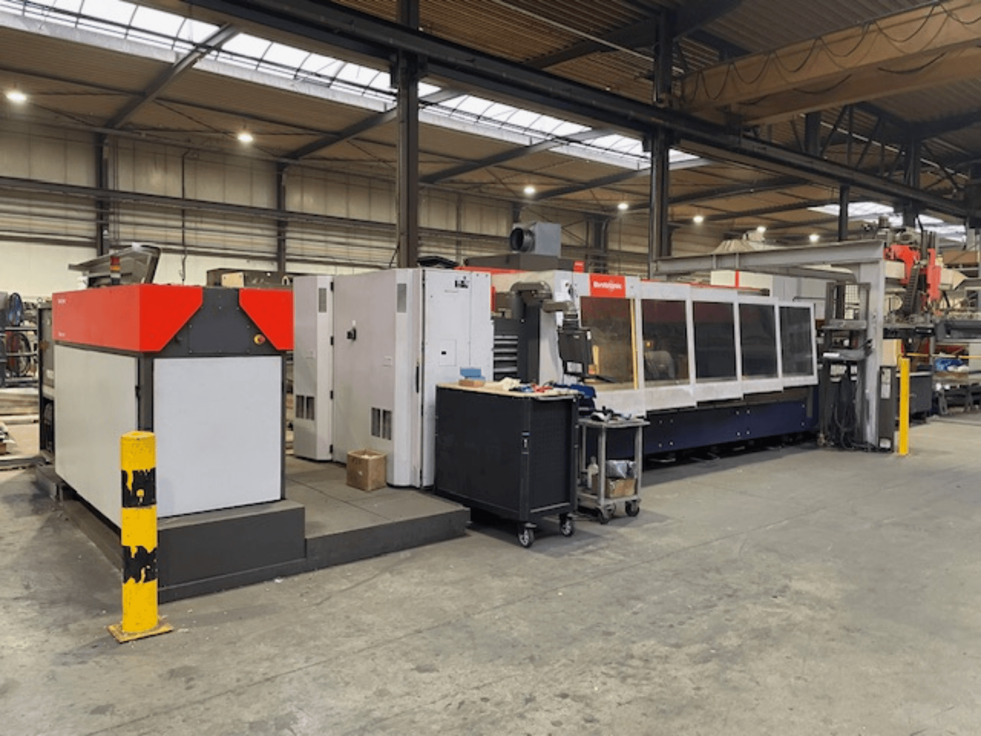 Bystronic BySpeed 3015 CO2-laserskärmaskin, sidovy i en verkstad, med tydliga röda och grå designelement.