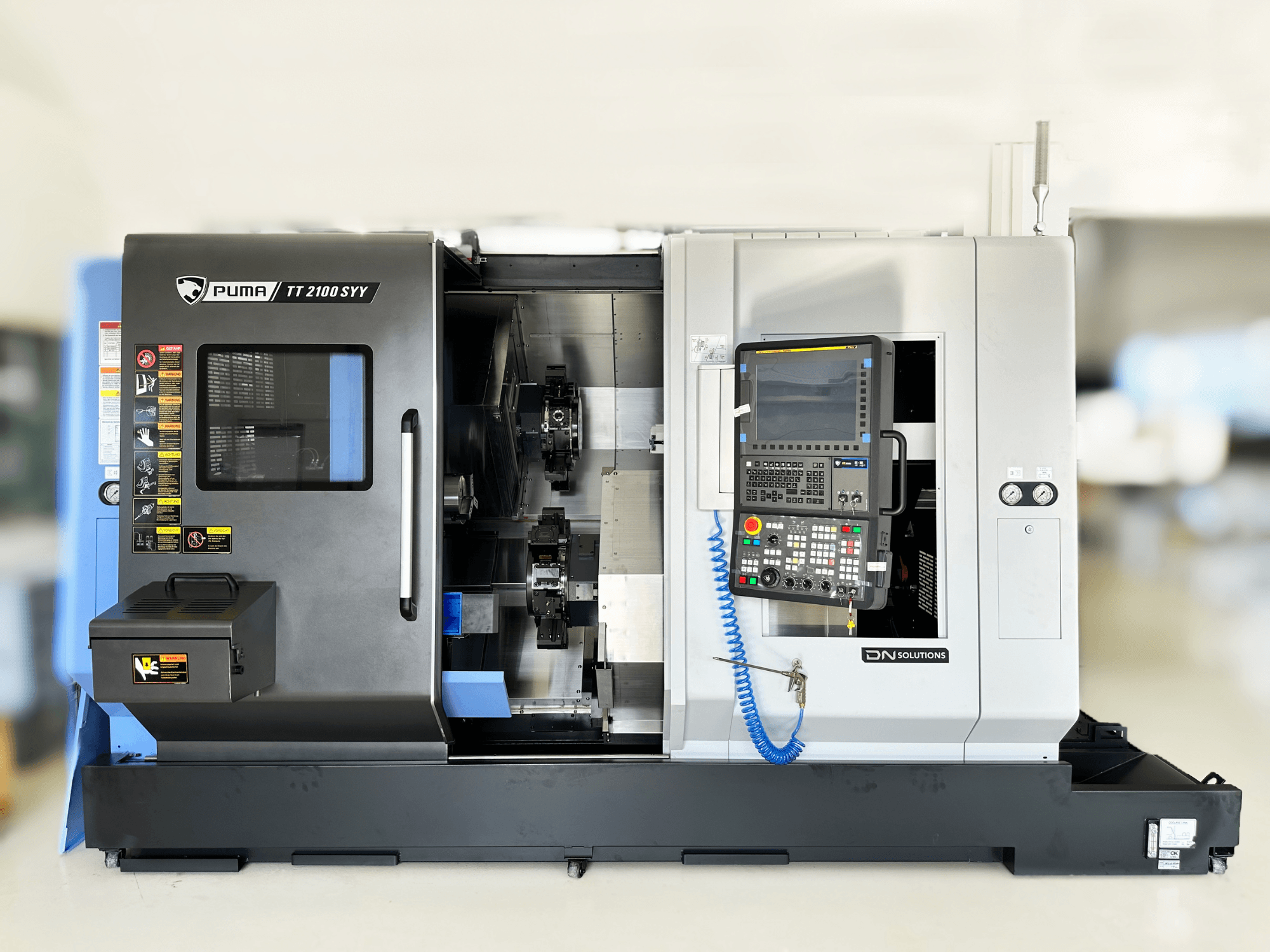 Svarv- och fräscenter DN SOLUTIONS PUMA TT2100SYY framifrån med kontrollpanel och synliga inre komponenter.