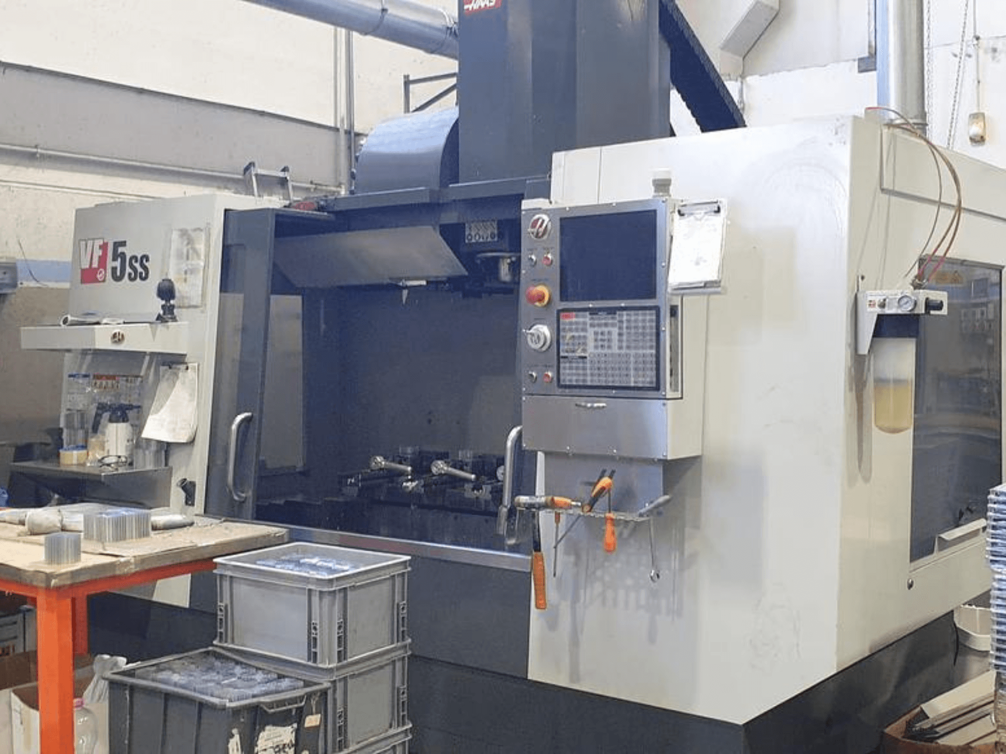 HAAS VF-5SS vertikal fleroperationsmaskin framifrån, med kontrollpanel, arbetsyta och förvaringsfack.