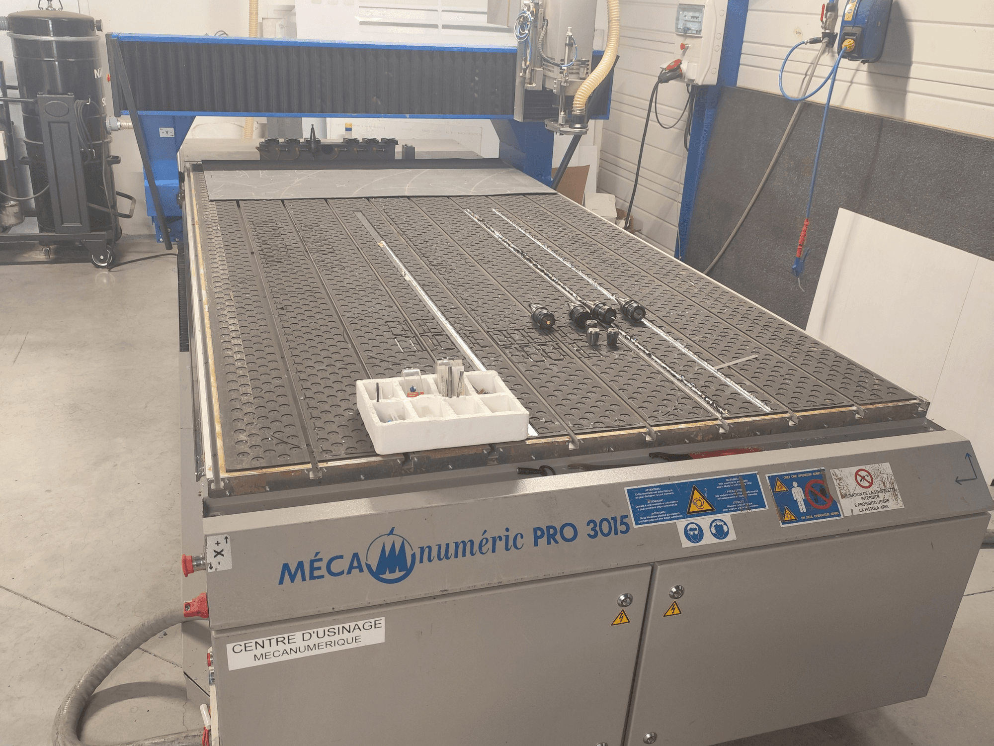 CNC-fräs MECANUMERIC Pro 3015, framifrån, med en detaljerad skärbänk, kontrollpanel och tillbehör på bordet.