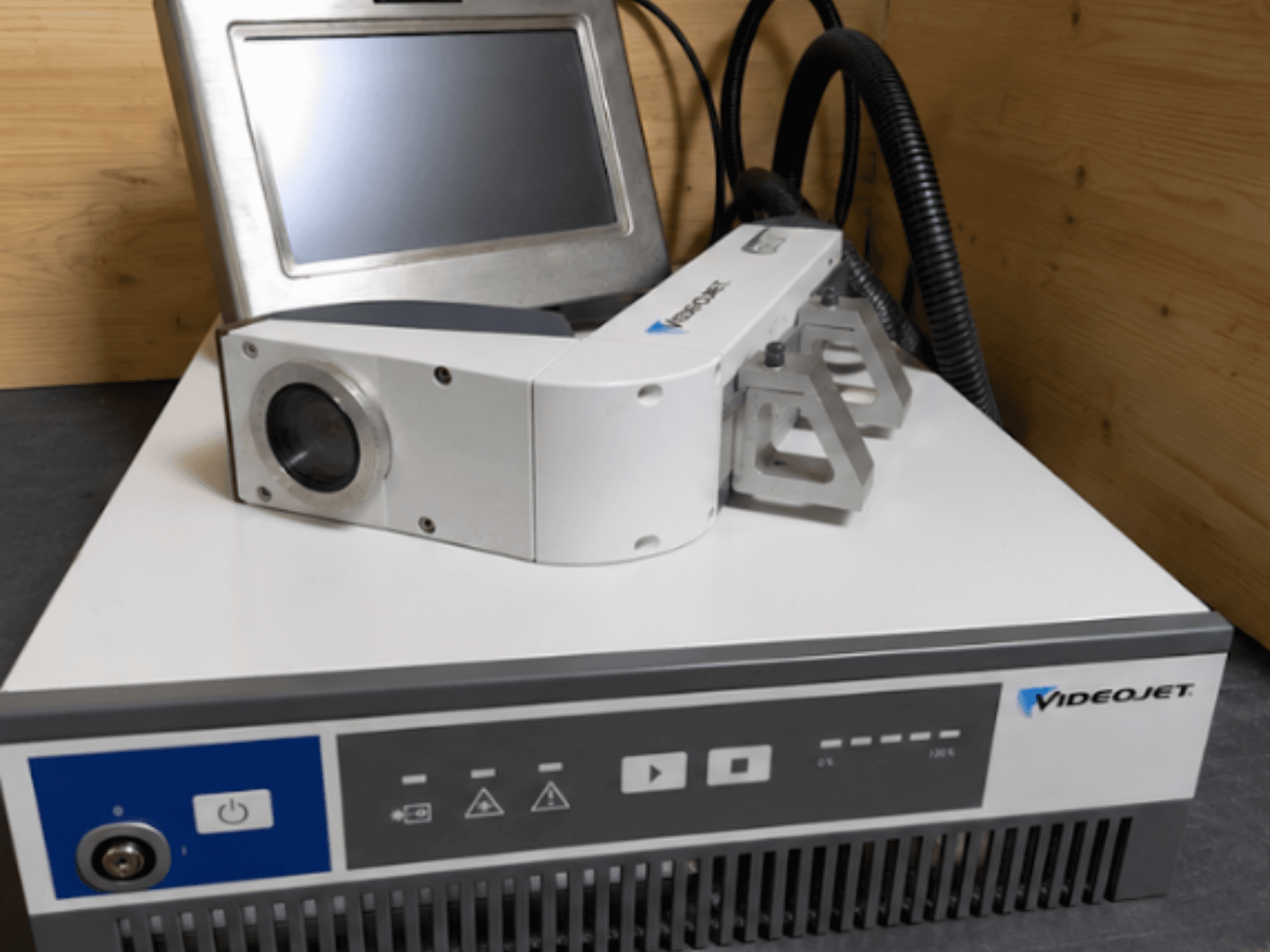Videojet 7230 Lasergraveringsmaskin, framifrån, visar kontrollpanel och laserhuvud med lins och tillbehör.