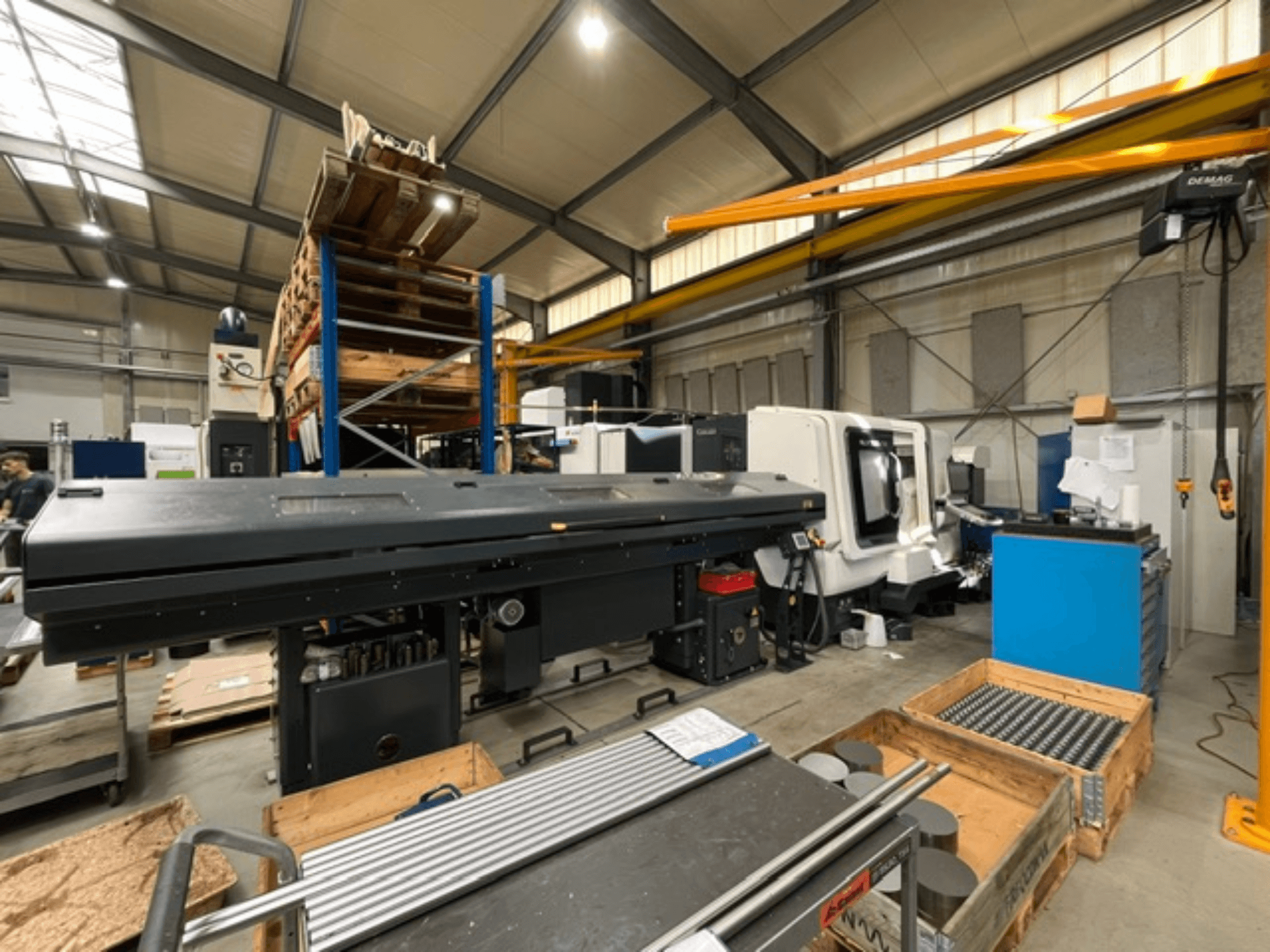 En horisontell svarv av typen DMG MORI MORI NLX 2500/700 SY i fabriksmiljö, sedd från sidan, med verktyg och pallar synliga.
