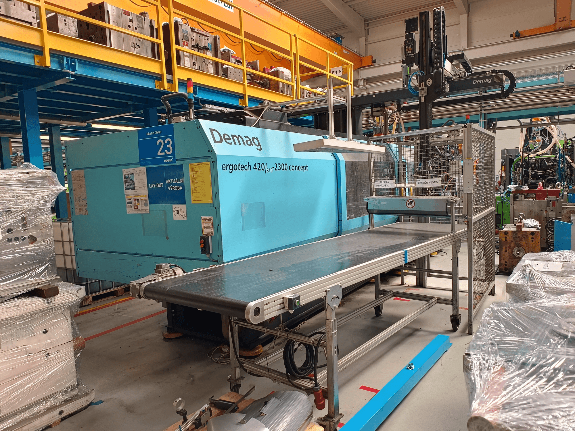 Demag ergotech 420/810 - 2300 hydraulisk formsprutningsmaskin i sidovy, med transportör och säkerhetshölje.