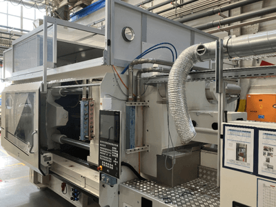 Industrimaskin från märke X, sidovy som visar kontrollpanel, kanalsystem och maskinkomponenter i en fabriksmiljö.
