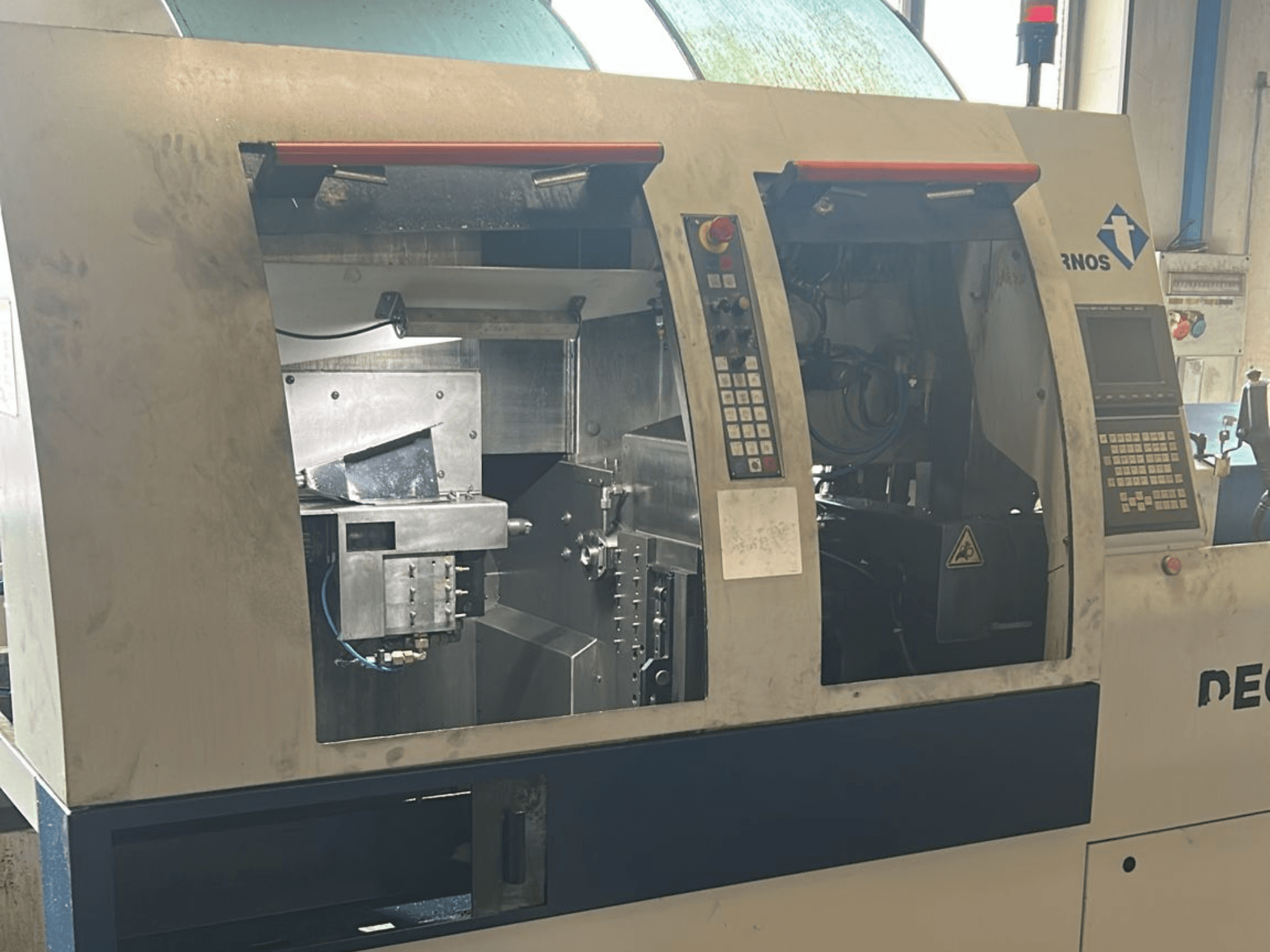 Alt text: Frontvy av TORNOS Deco 13 b svarv av schweizisk typ med synliga kontrollpaneler och interna komponenter.