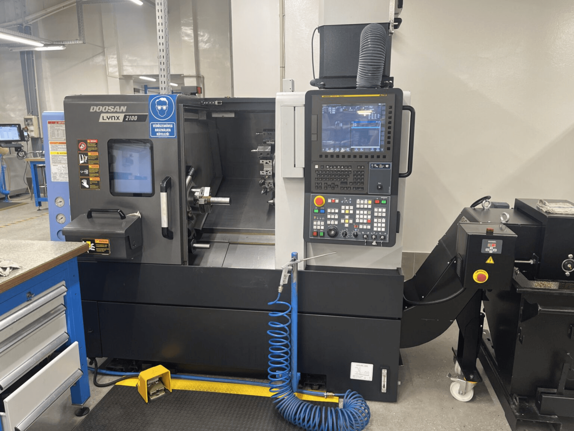 Frontvy av en DOOSAN Lynx 2100A horisontell svarv, som visar kontrollpanelen och spindelområdet med anmärkningsvärda säkerhetsfunktioner.