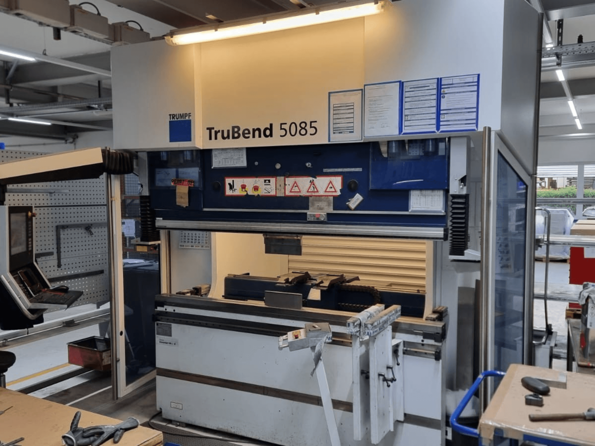 TRUMPF TruBend 5085 bockningsmaskin, framifrån, visar kontrollpanel, manöverstation och säkerhetsvarningar inne i verkstaden.