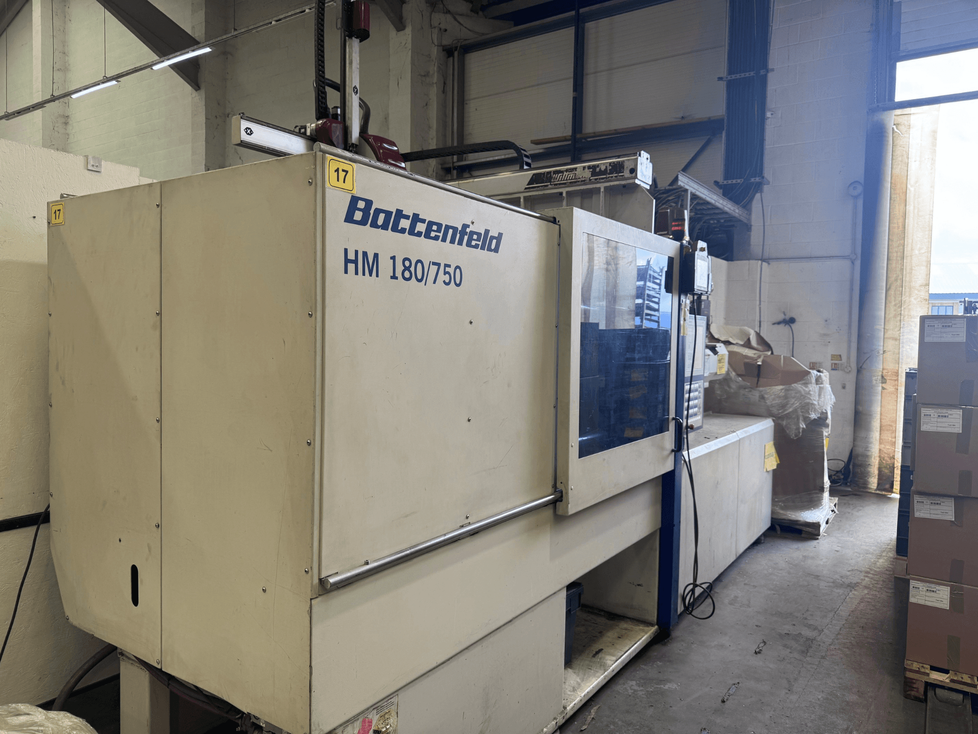 Battenfeld HM150750 hydraulisk formsprutningsmaskin sedd framifrån, med kontrollpanel och omgivande utrustning.