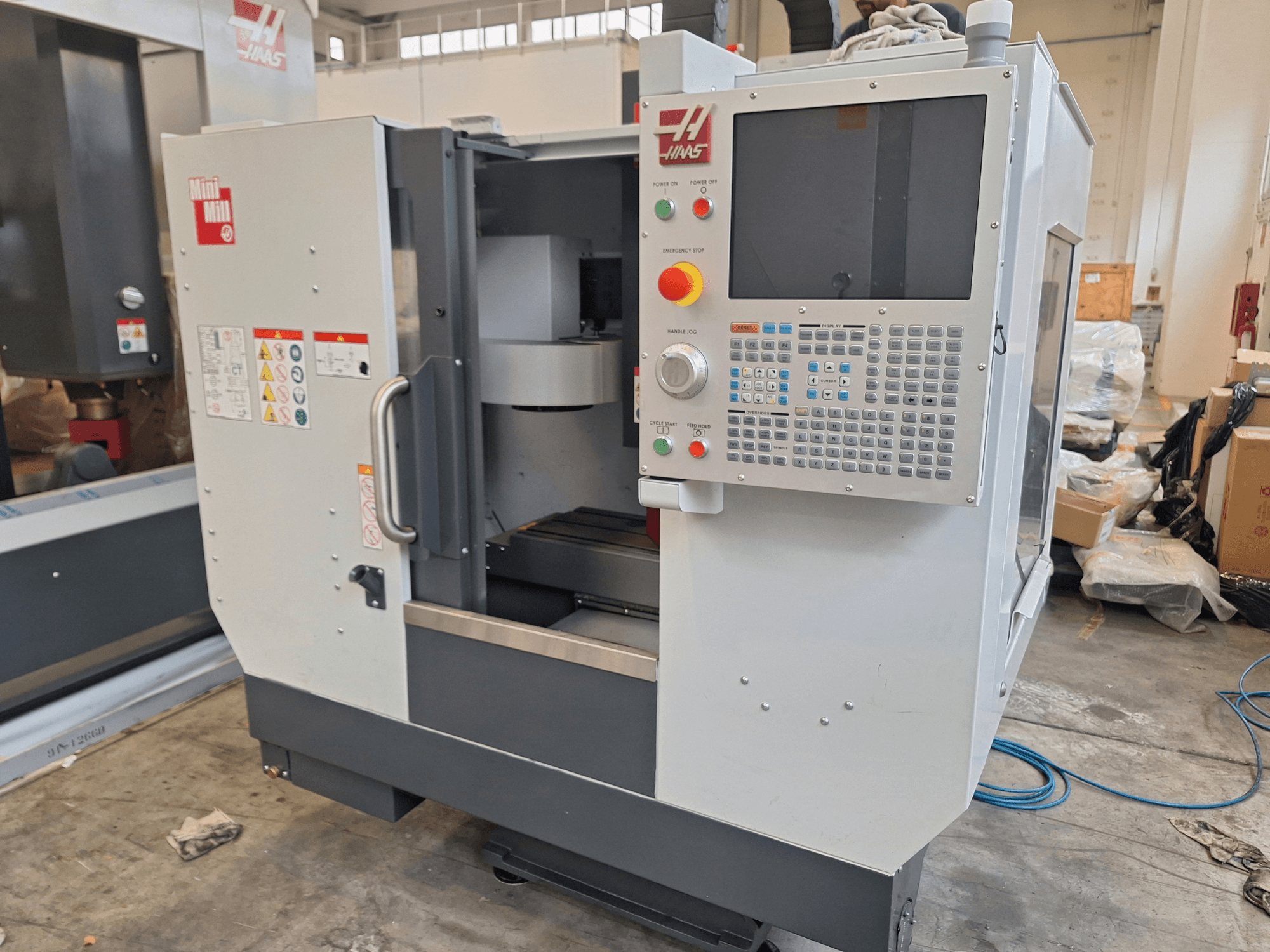 HAAS Mini Mill – vertikalt bearbetningscenter sett framifrån, med en kontrollpanel försedd med knappar och en skärm.