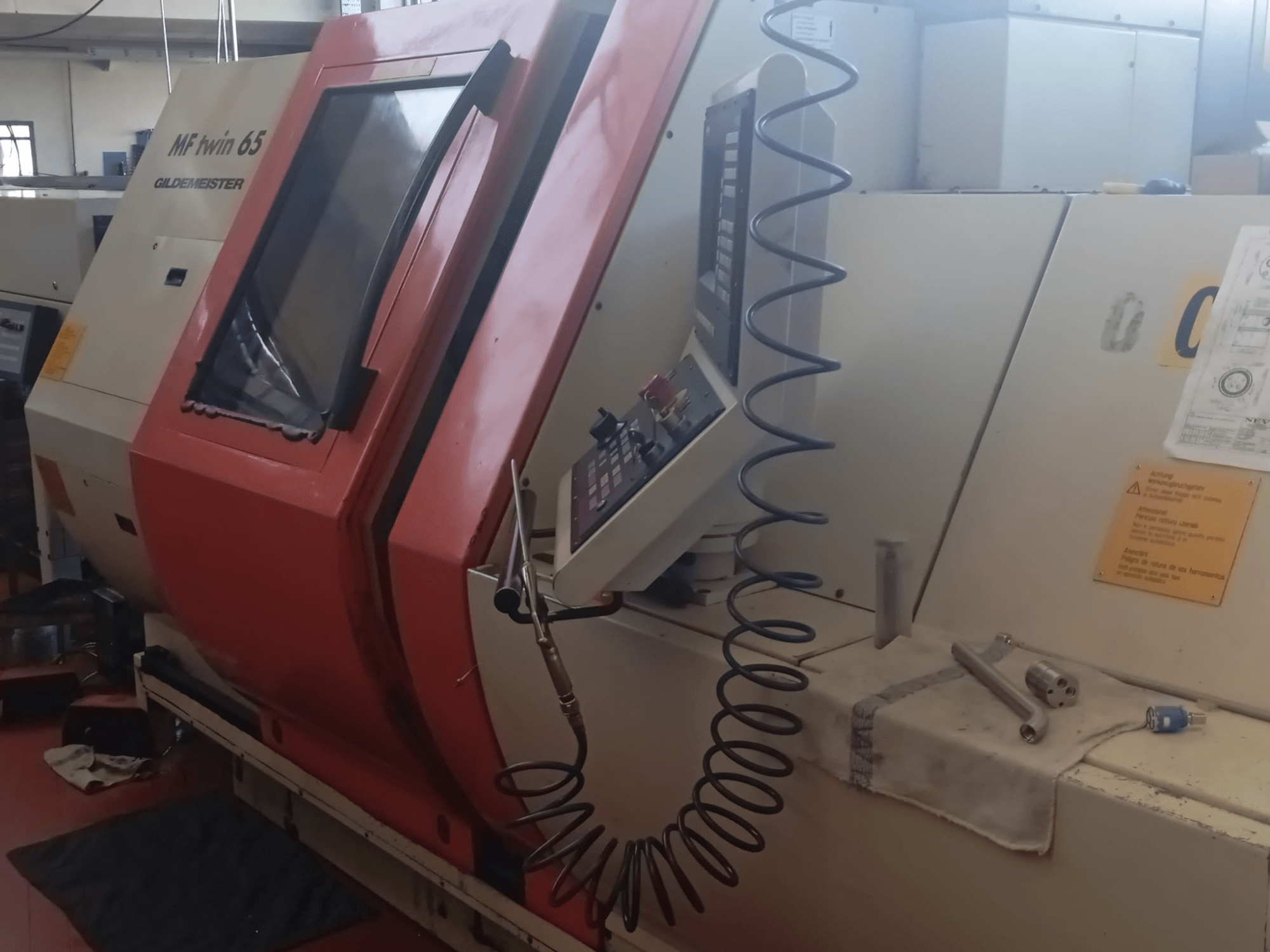 Orange och vit MF twin 65 Gliedemeister-maskin, framifrån, med kontrollpanel och verktyg på en trasa.