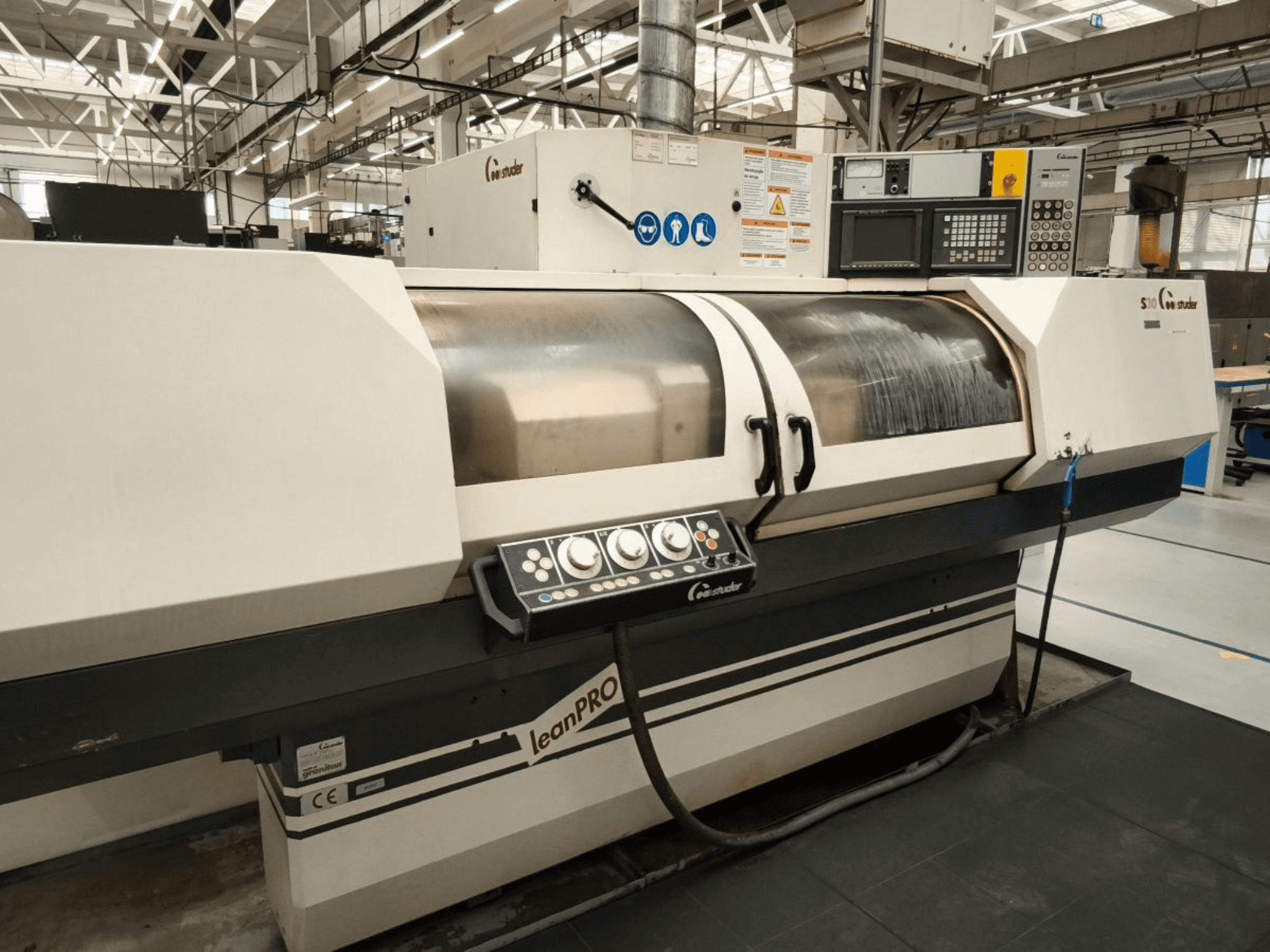 STUDER S30 LEAN PRO rundslipmaskin, sidovy, visar kontrollpanelen och slipskivans lock i en industriell miljö.