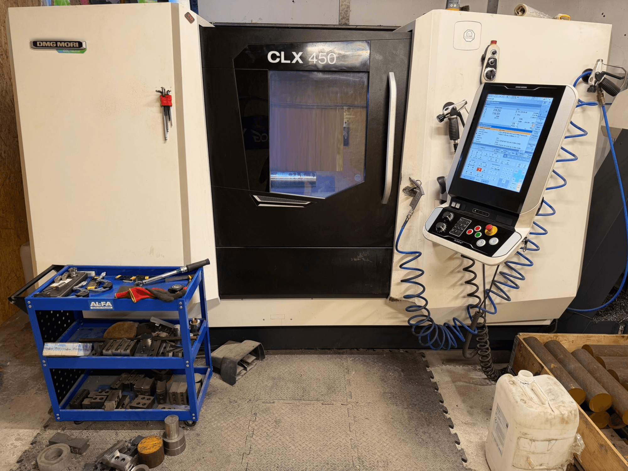 DMG MORI CLX 450 V3 horisontell svarvmaskin framifrån, med kontrollpanel och närliggande verktygsvagn med utrustning.