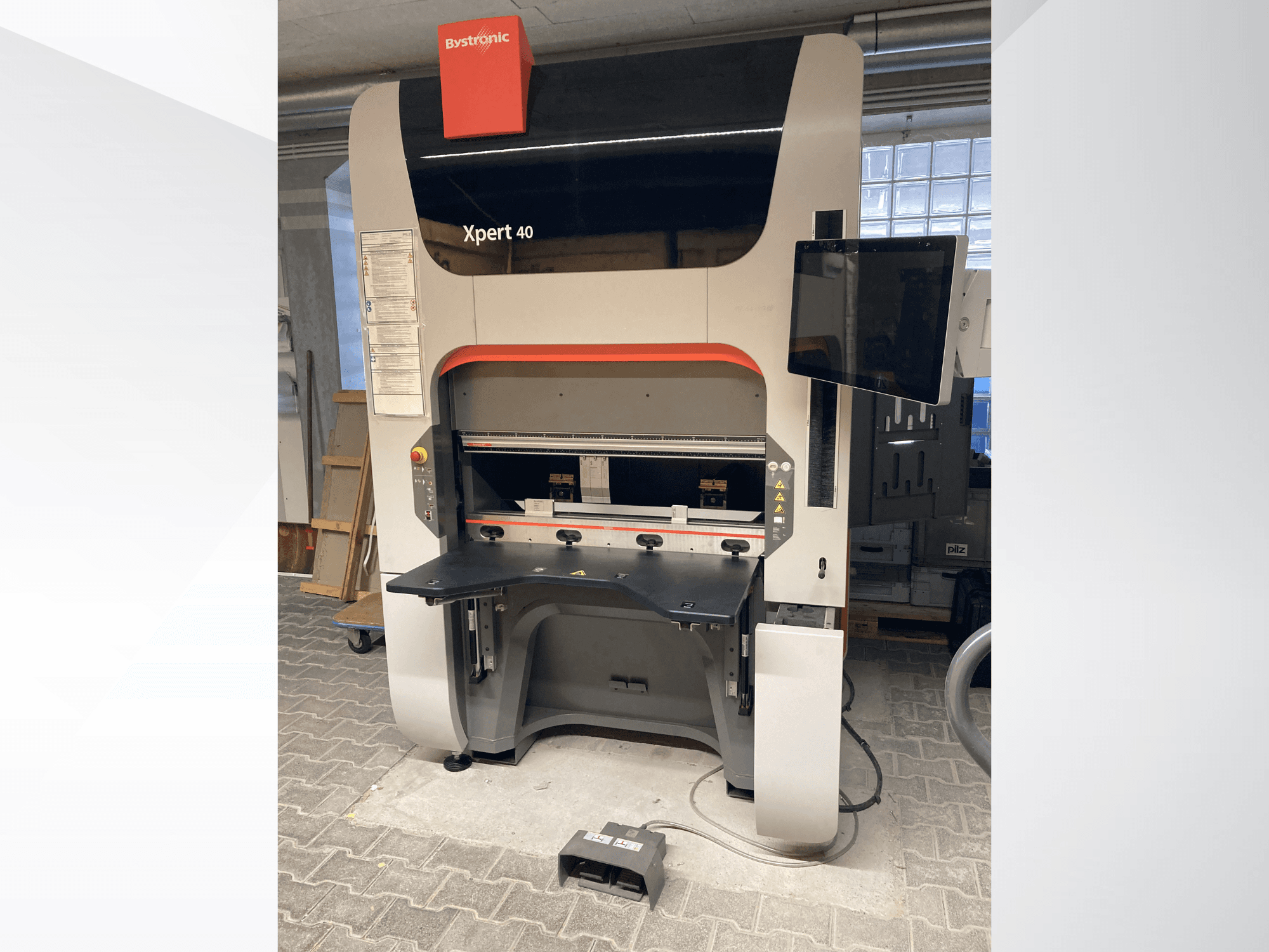 Bystronic Xpert 40/1030 kantpress framifrån, med kontrollpanel, arbetsyta och ansluten bildskärm.