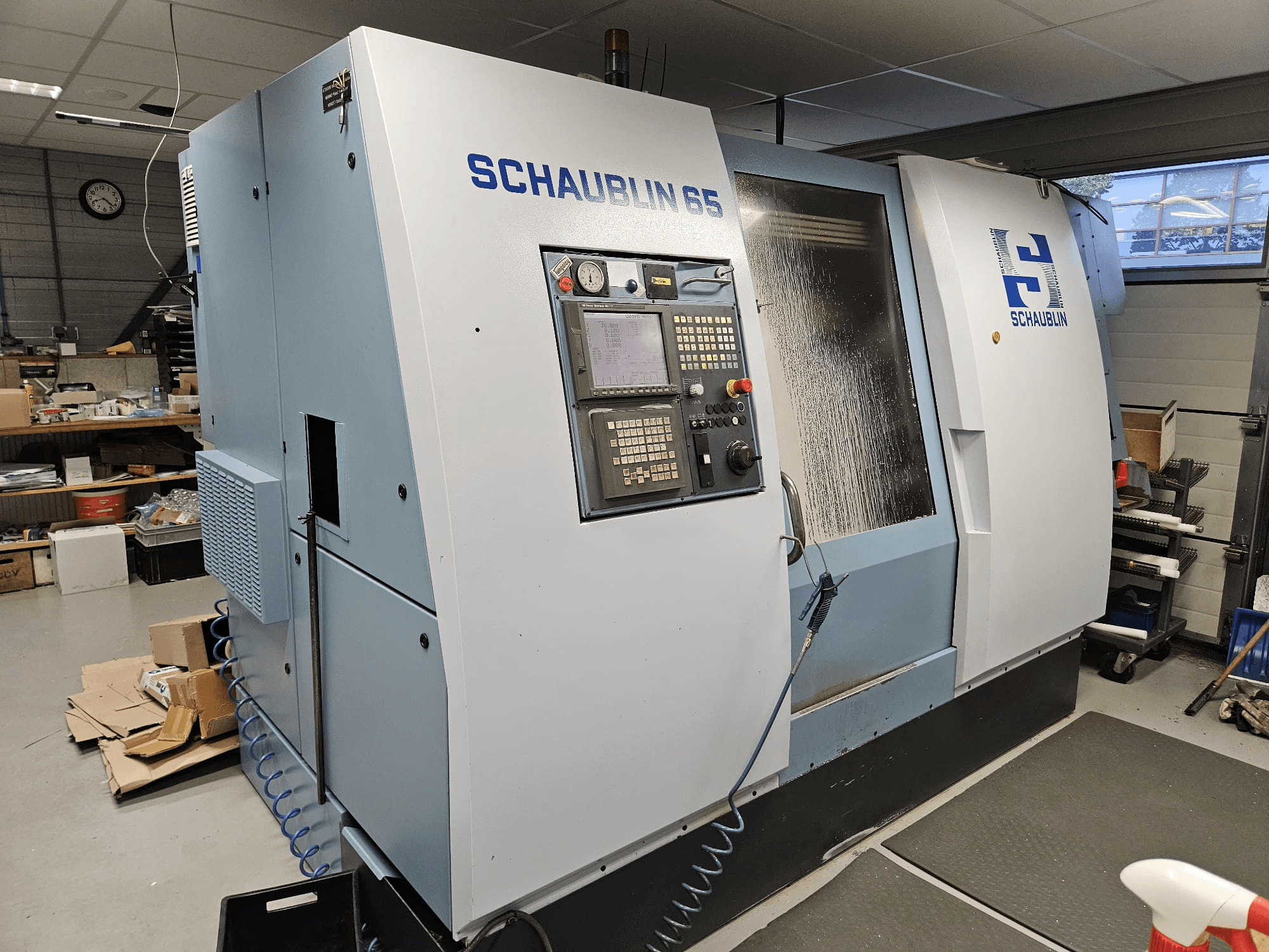 SCHAUBLIN 65 CNC-maskin, sidovy, med kontrollpanel, blått och grått hölje och synligt kylsystem.