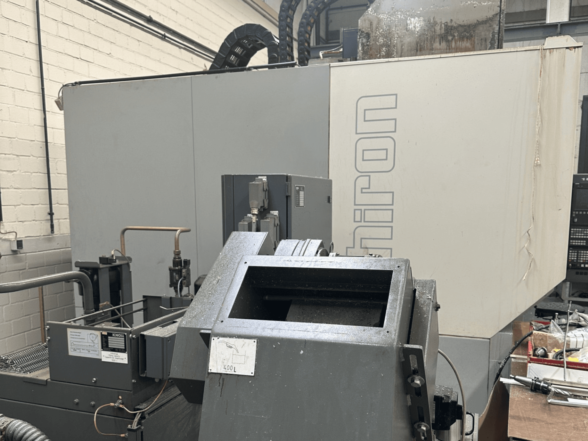 VARUMÄRKE: Chiron; Framsida av industriell CNC-maskin med grå exteriör, synlig kontrollpanel och maskinkomponenter i fokus.