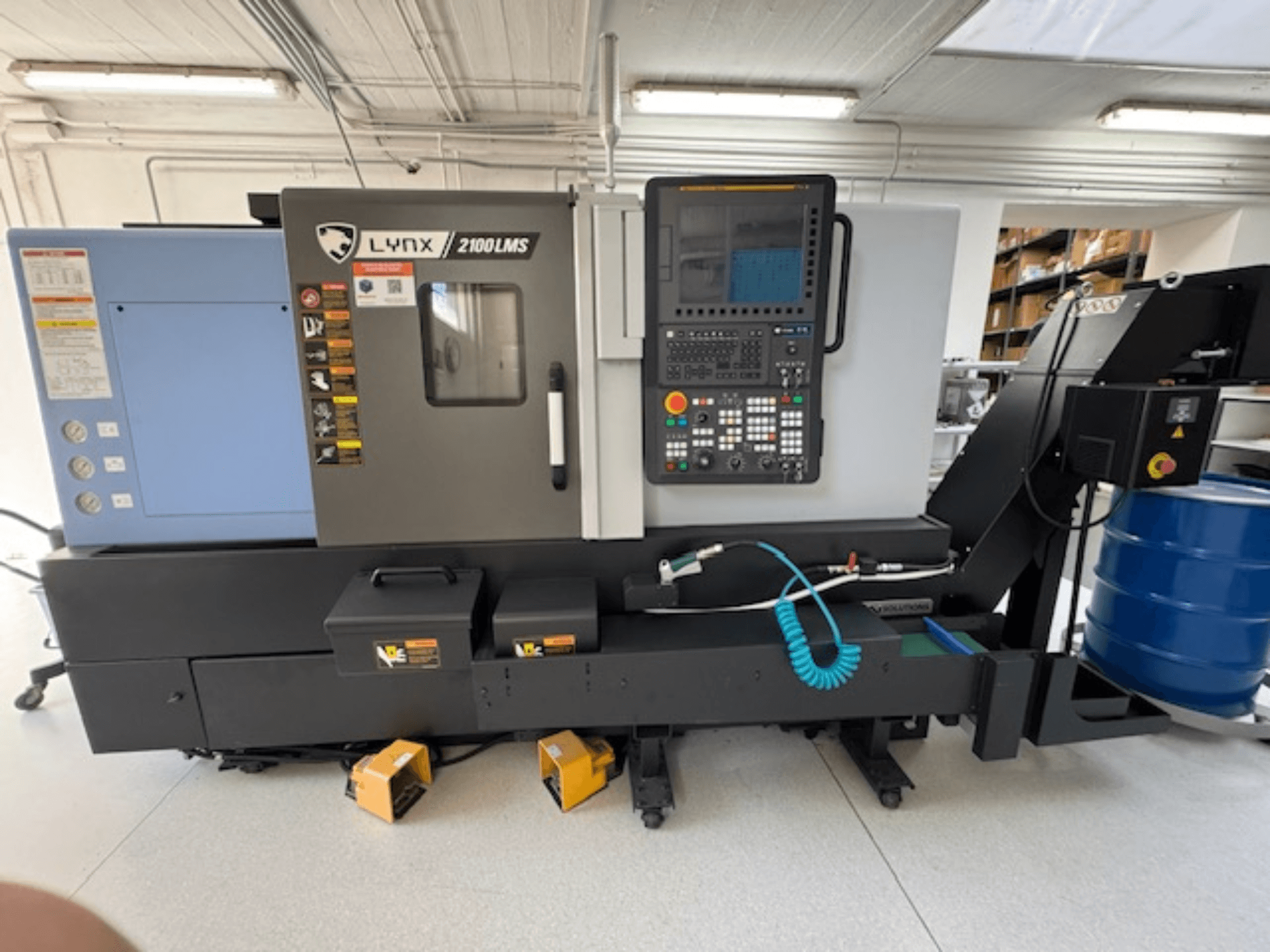 DOOSAN LYNX 2100LMSA horisontell svarv, framifrån, med kontrollpanel, kylvätskeslang och förvaringslådor.