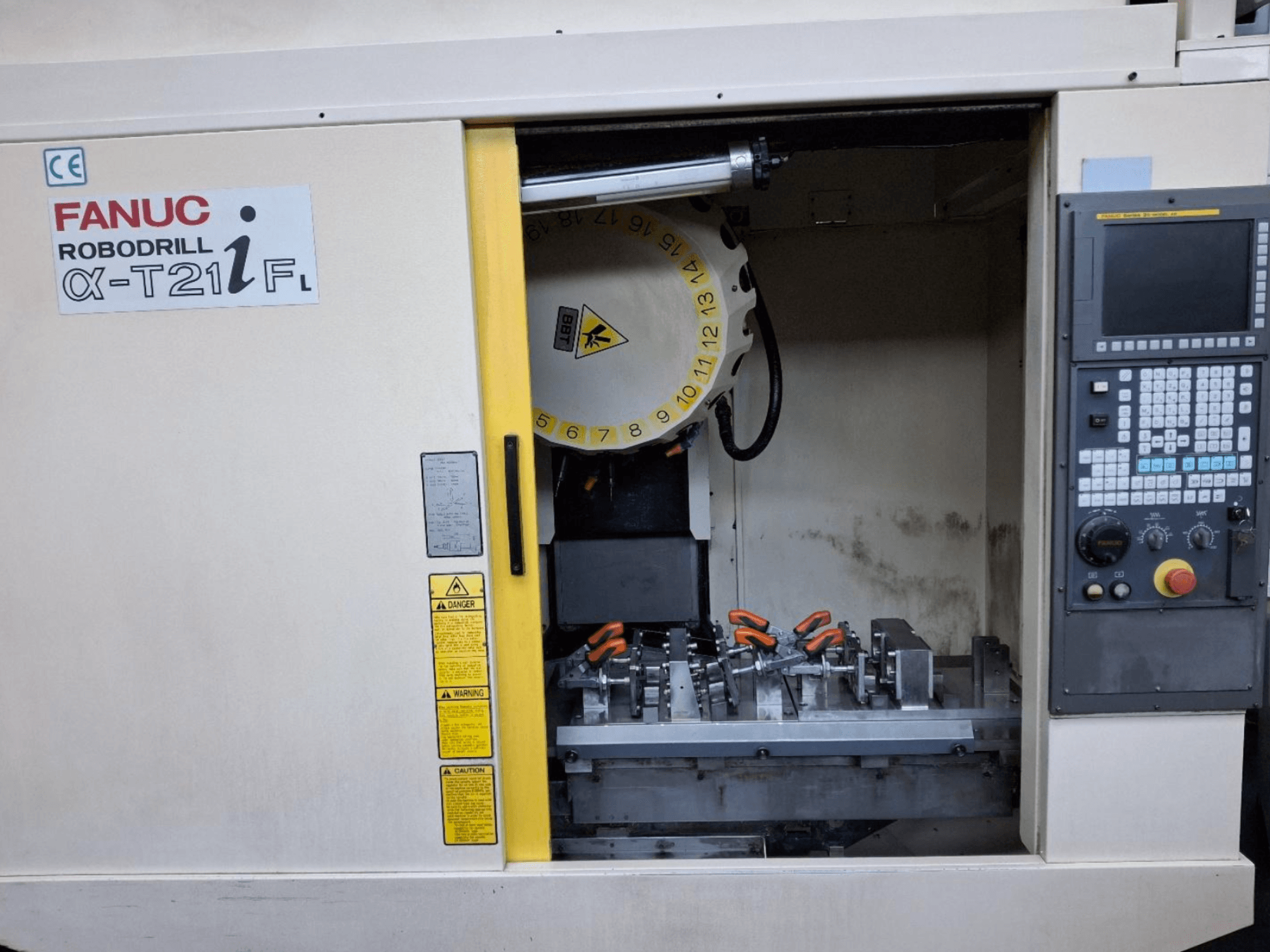 FANUC ROBODRILL α-T21iFL vertikalt bearbetningscenter framifrån, med verktyg och reglage inuti maskinskåpet.