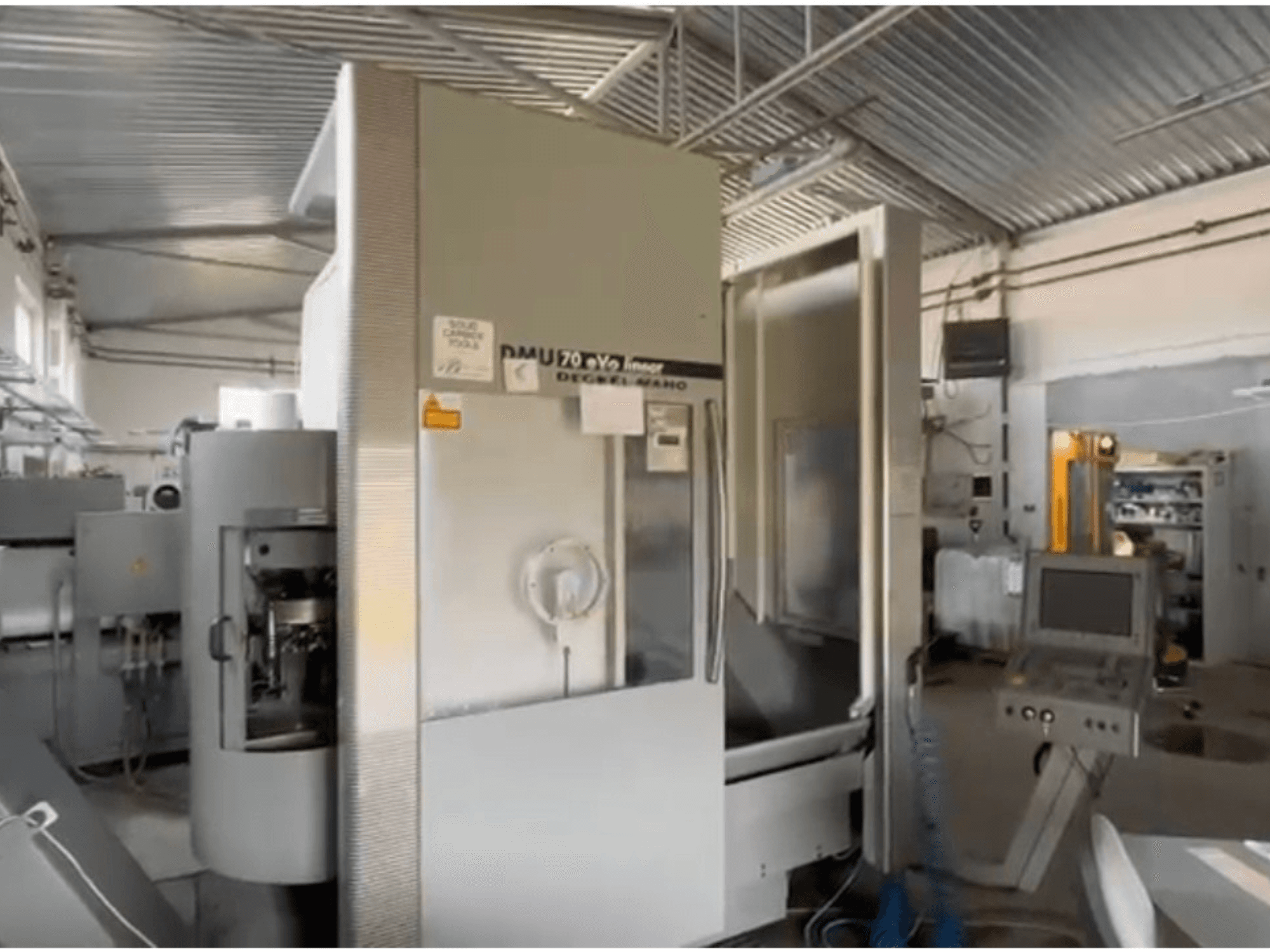 DMU 70 eVo linjär CNC-maskin i en verkstad, vy framifrån, med kontrollpanel och modern design.