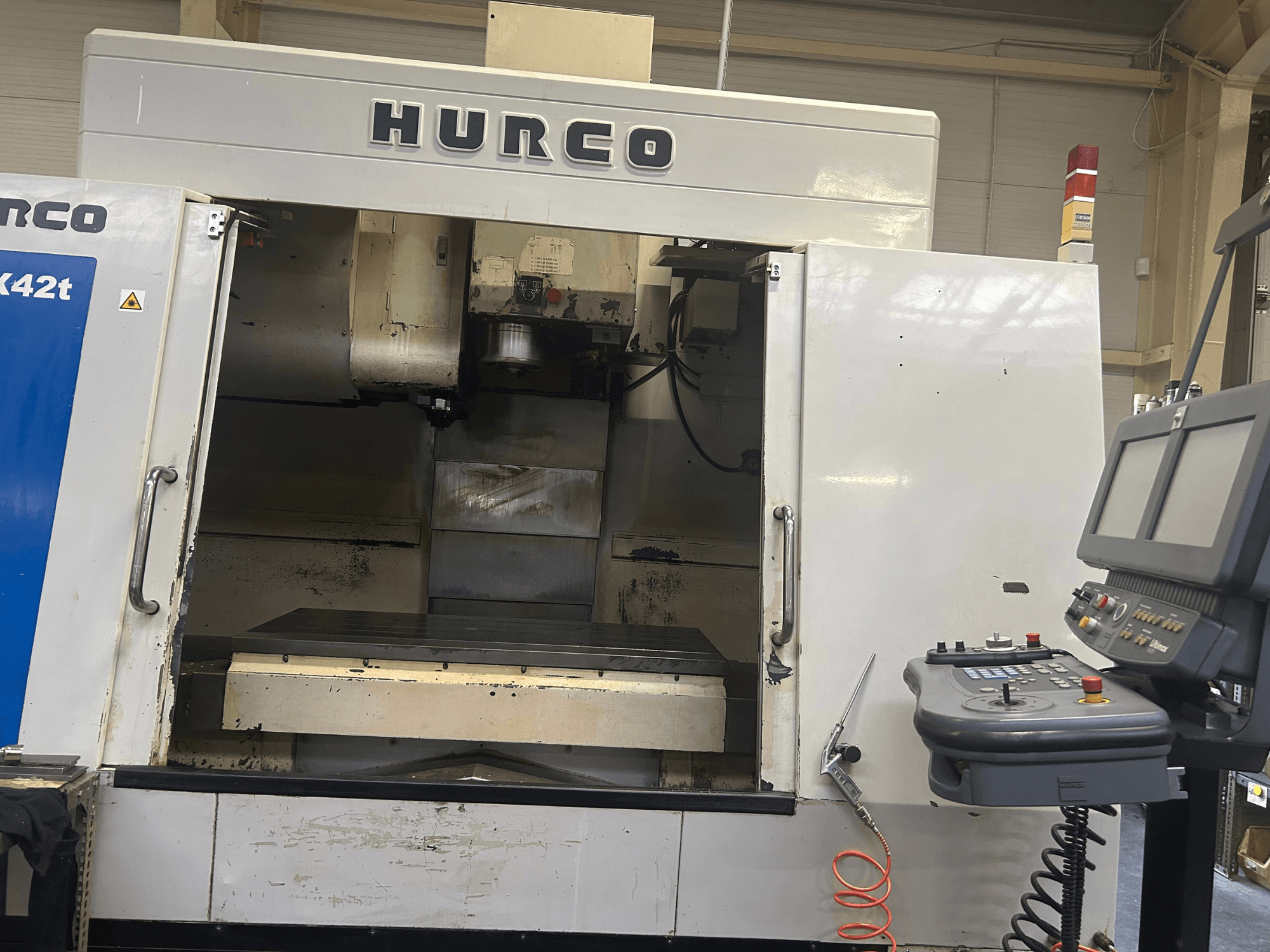 Hurco VMX42T CNC-fräsmaskin framifrån, med öppen arbetsyta och kontrollpanel med knappar och display.