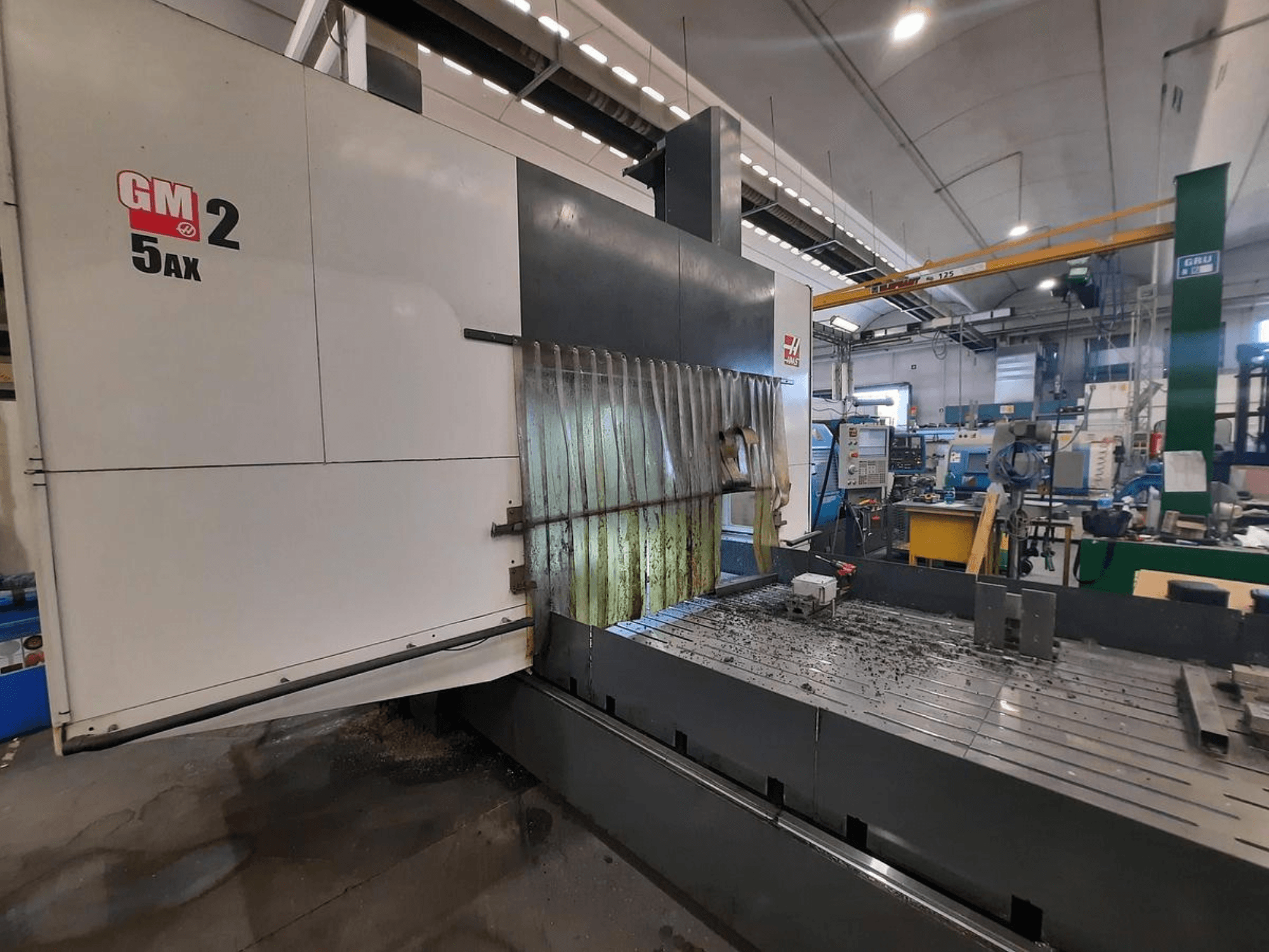 GM 2 5AX CNC-maskin i en verkstad, sidovy, visar arbetsområdet och metallspån på bäddens yta.
