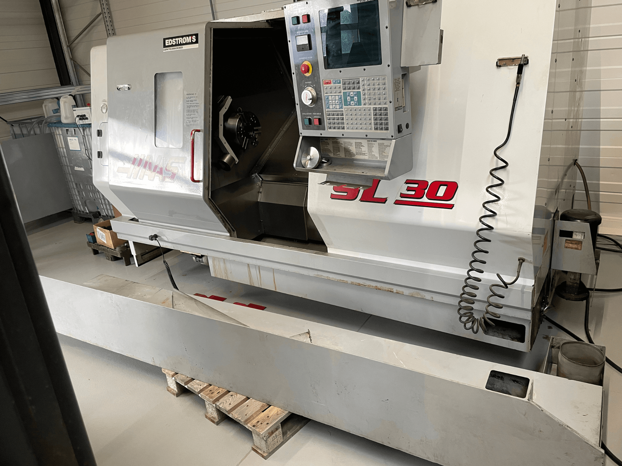 Haas SL 30 CNC-svarvmaskin i en verkstad, sidovy, med kontrollpanel och öppen spindel för bearbetningsuppgifter.